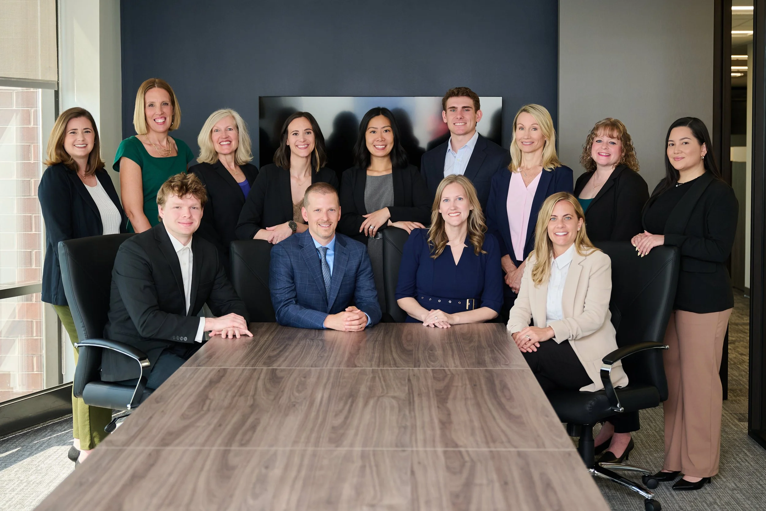 Group of professionals gathered around a conference table in a modern office, smiling at the camera.