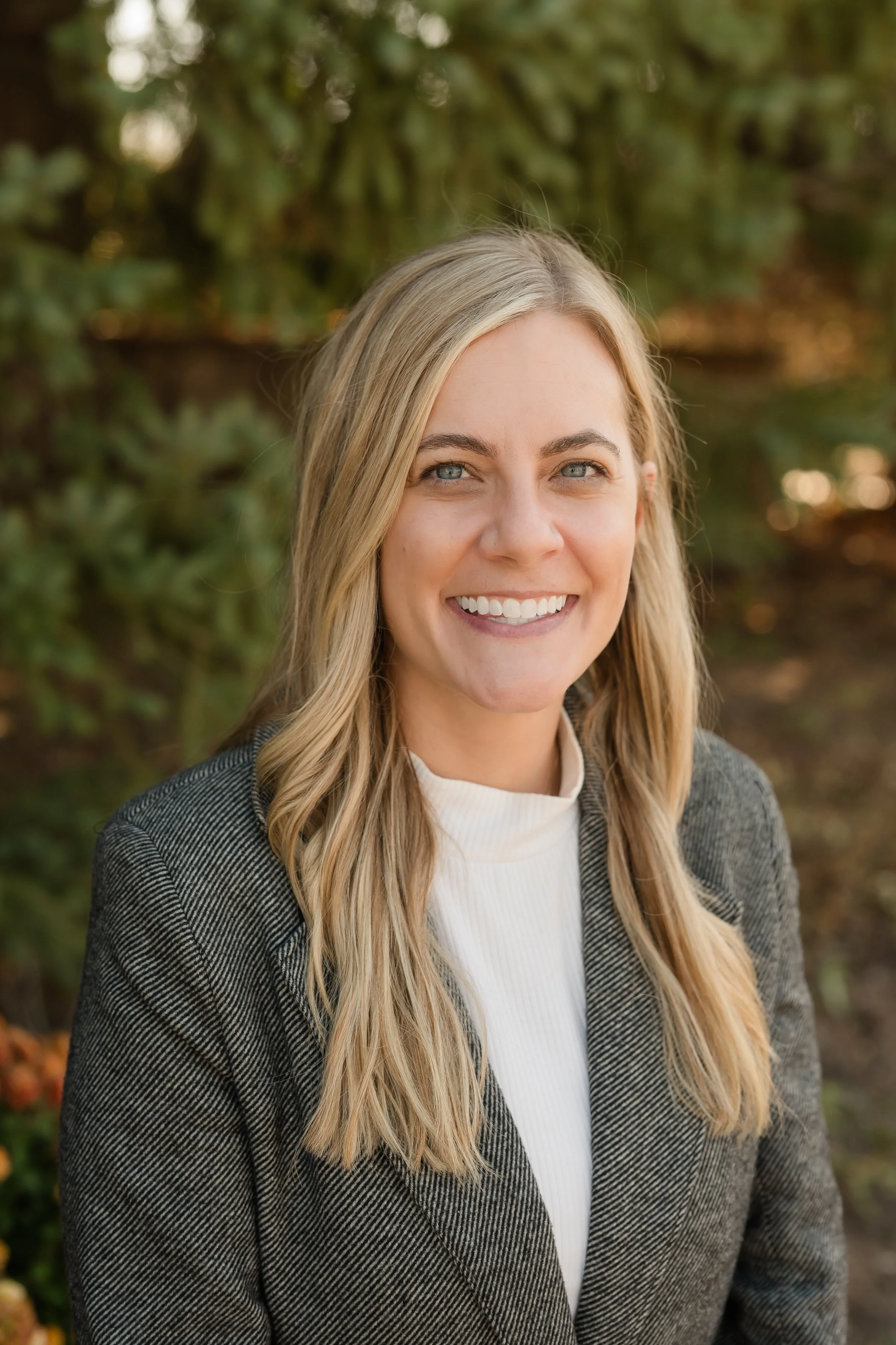 Four people, two children and two adults, smiling inside a warehouse surrounded by boxes and shelves. The children are wearing hairnets and the adults are standing close together with their arms around the children.
