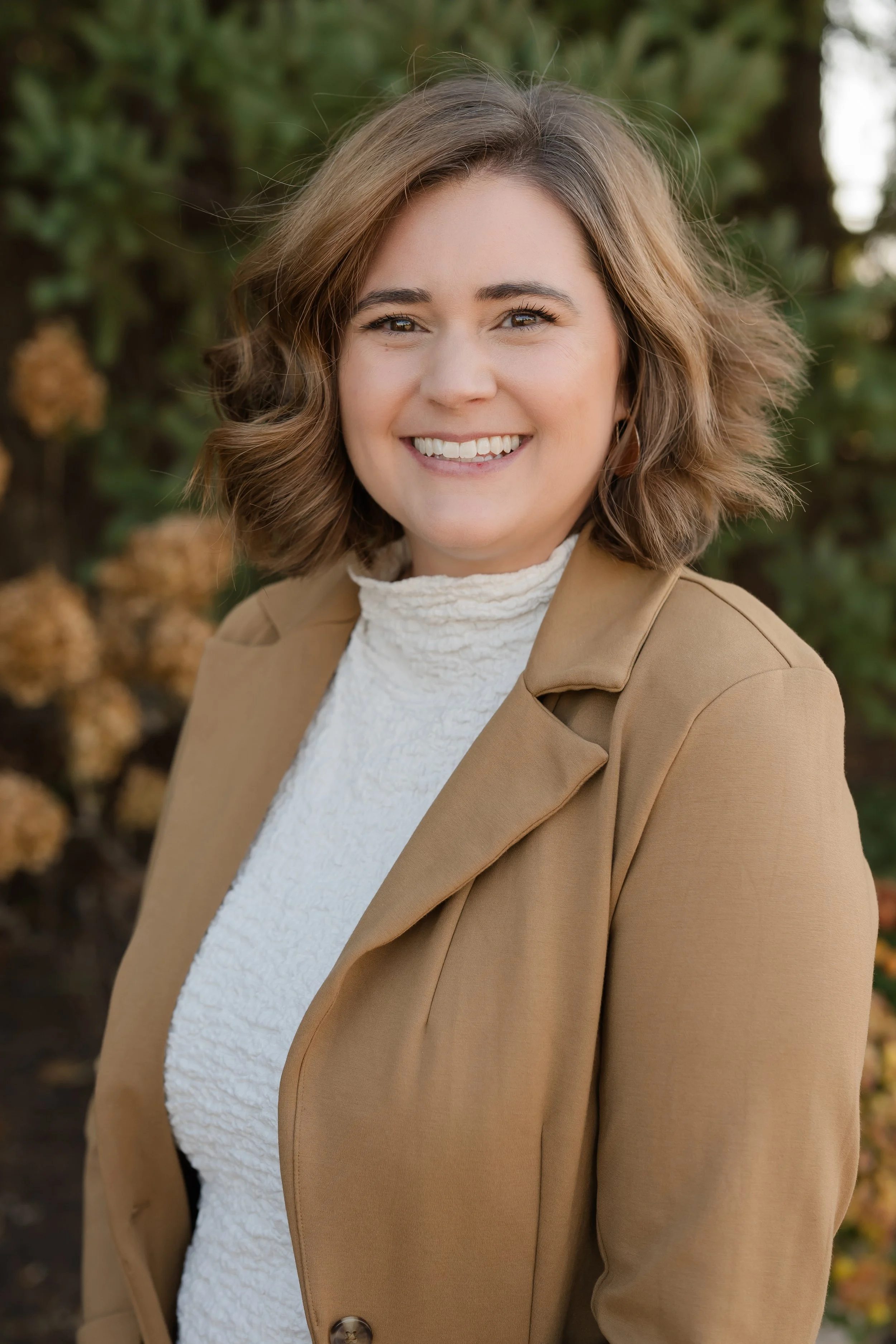 A smiling woman and man taking a selfie at the Museum of Ice Cream, with pink and red heart-shaped balloons in the background, and the woman holding a pink cup of ice cream.