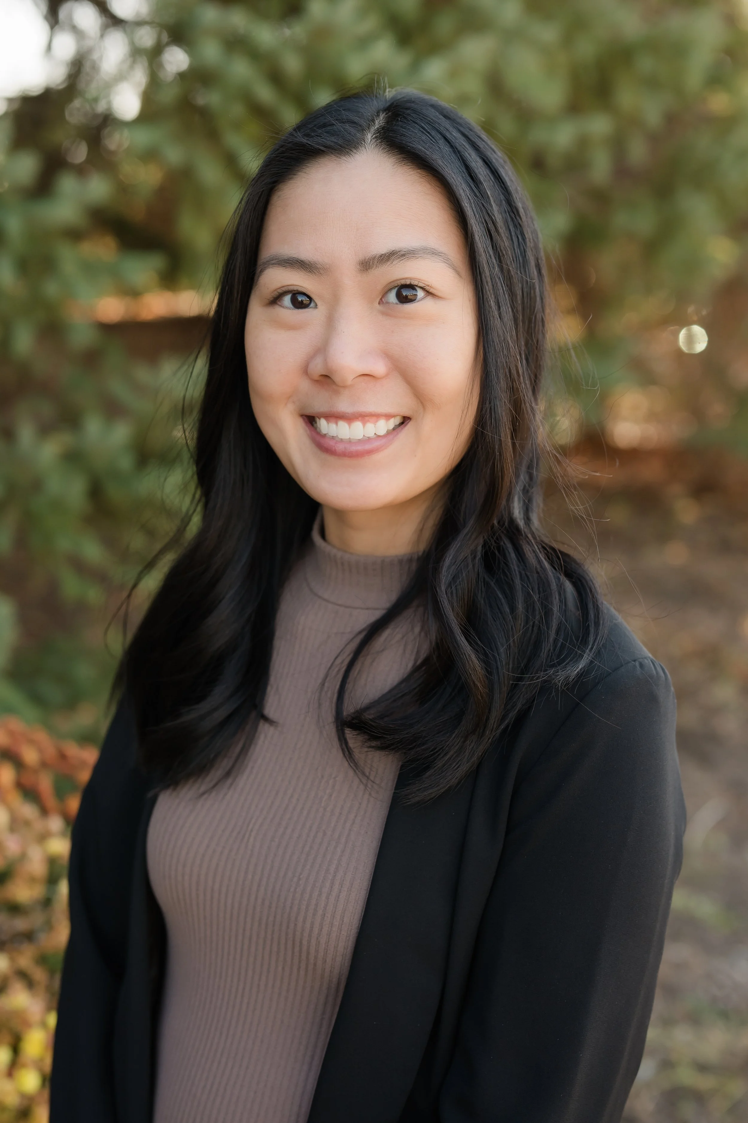 Family of four dressed in maroon and black, smiling outdoors in front of a white wall.
