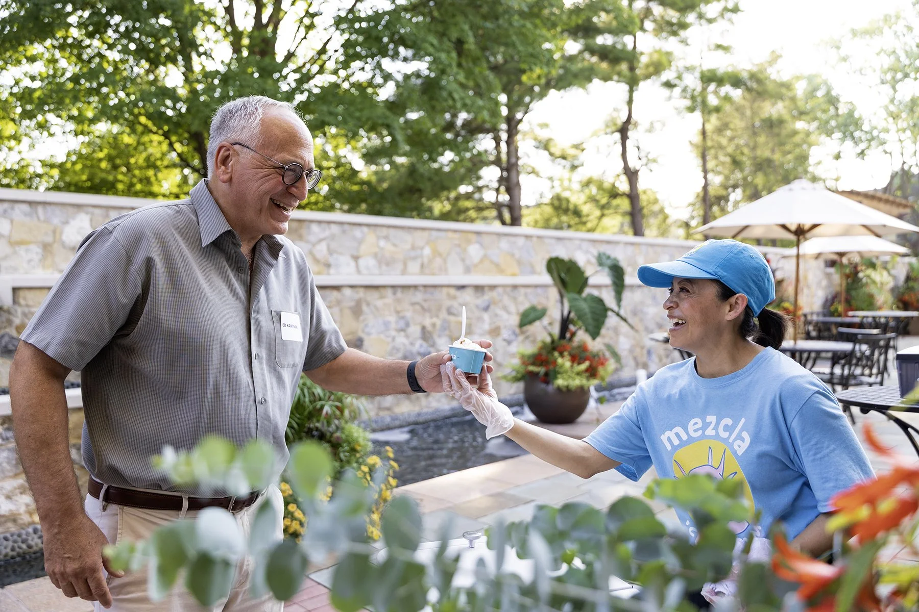 man getting handed ice cream from woman in blue hat