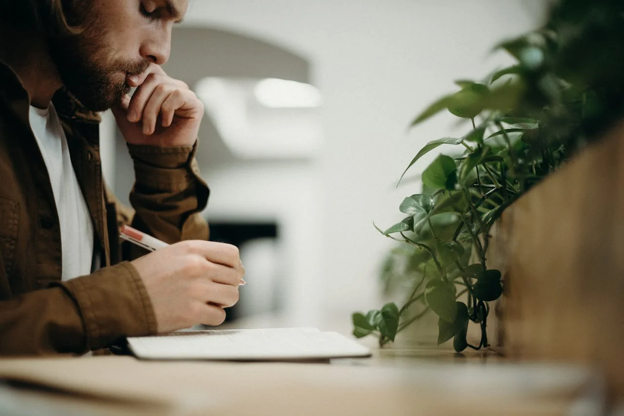 man-wearing-brown-jacket-using-pen
