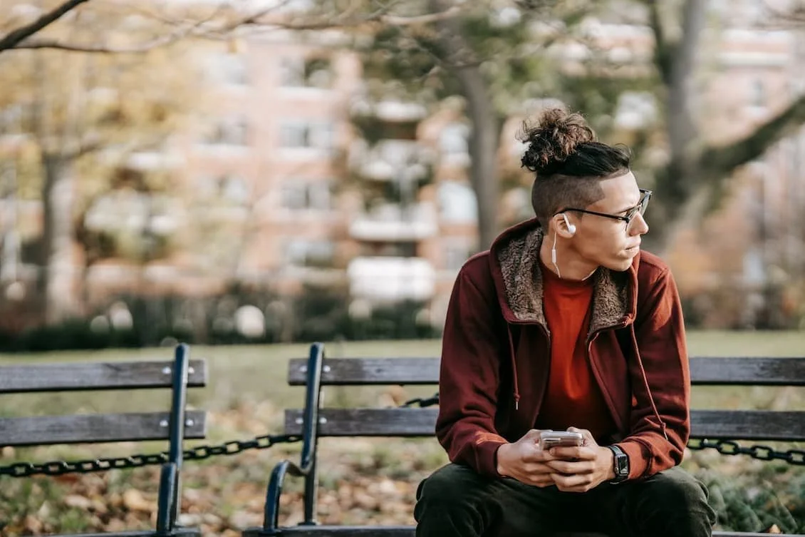 thoughtful-man-with-gadgets-in-fall-park