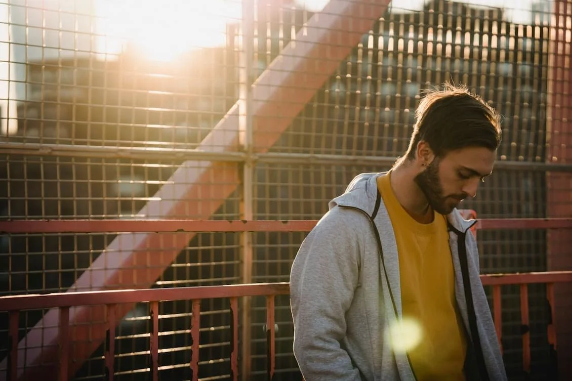 sad-bearded-man-on-city-bridge-in-sunlight