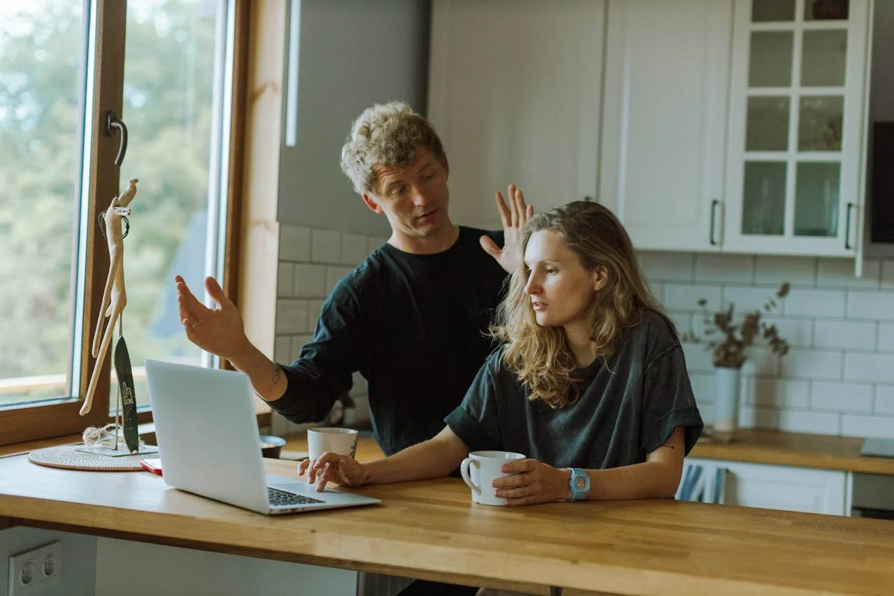 man-beside-a-woman-using-a-laptop-on-a-wooden-counter
