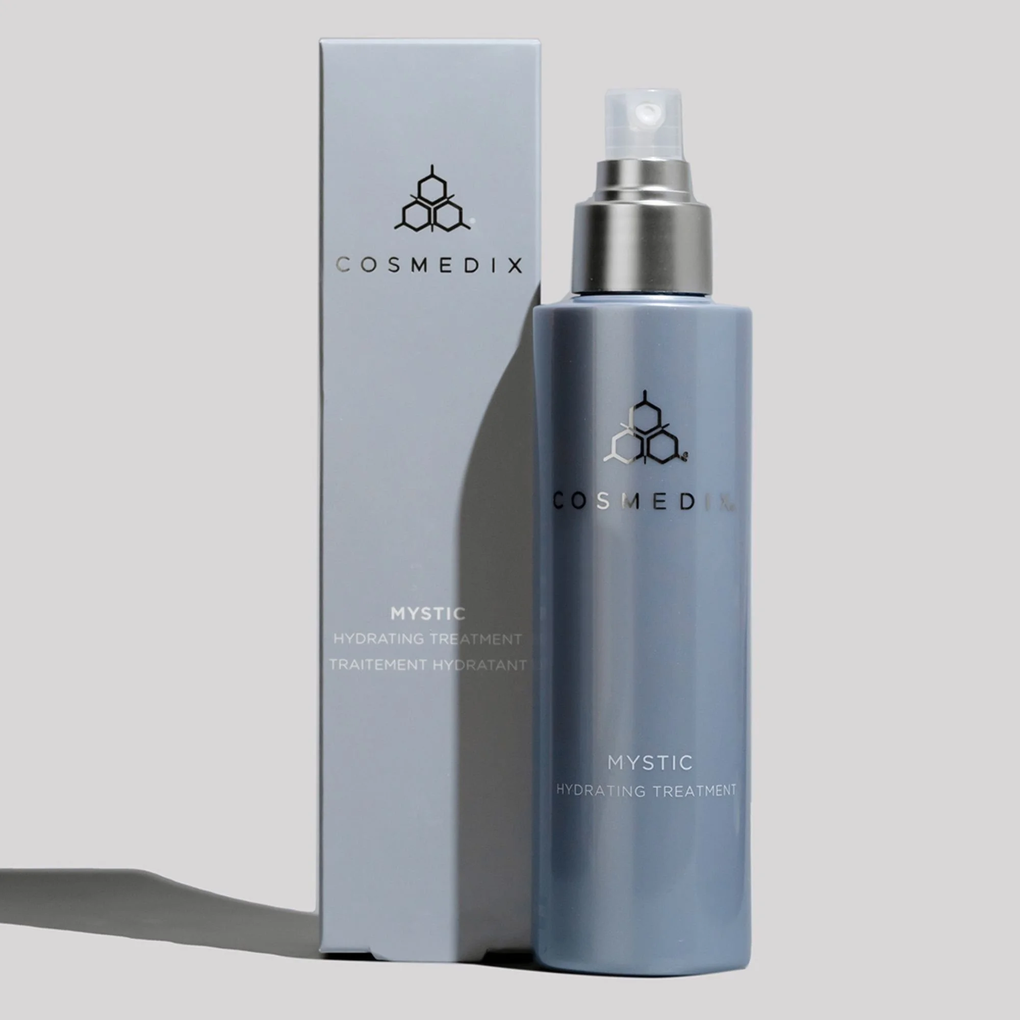 COSMEDIX Mystic Hydrating Treatment spray bottle with its box on a gray background.