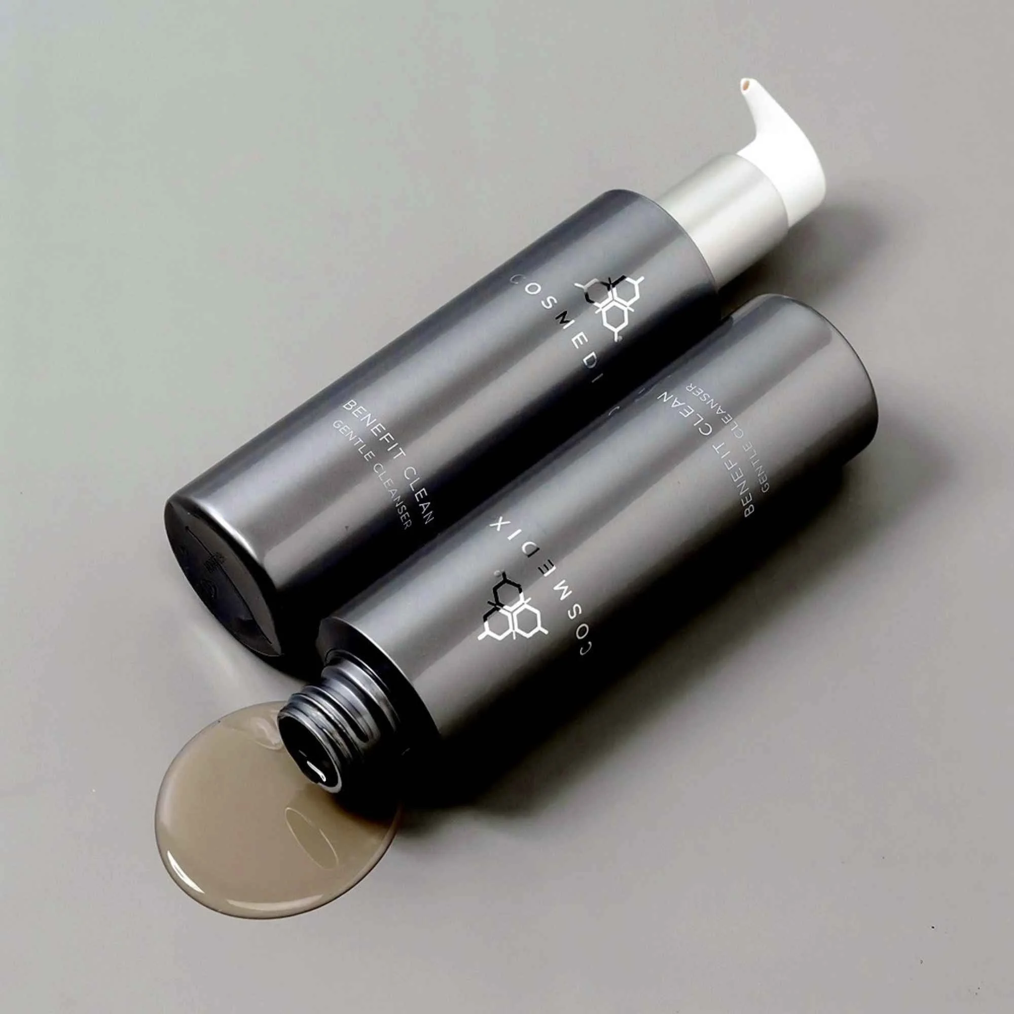 COSMEDIX Benefit Clean silver pump bottle shown horizontally beside a golden gel cleanser swatch.