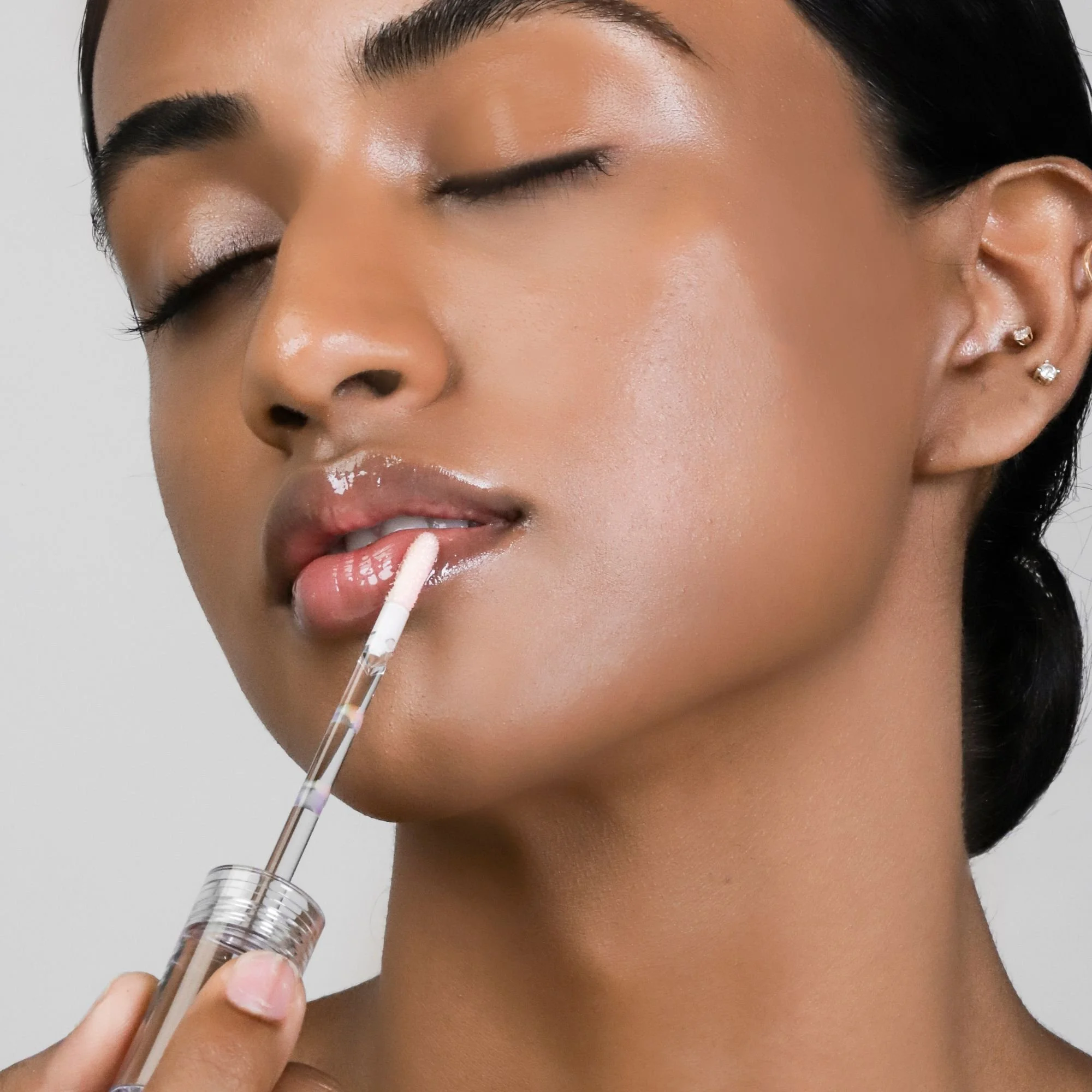 Close-up of the COSMEDIX Lumi Crystal lip hydrator model with black skin aplying to boost hydration.