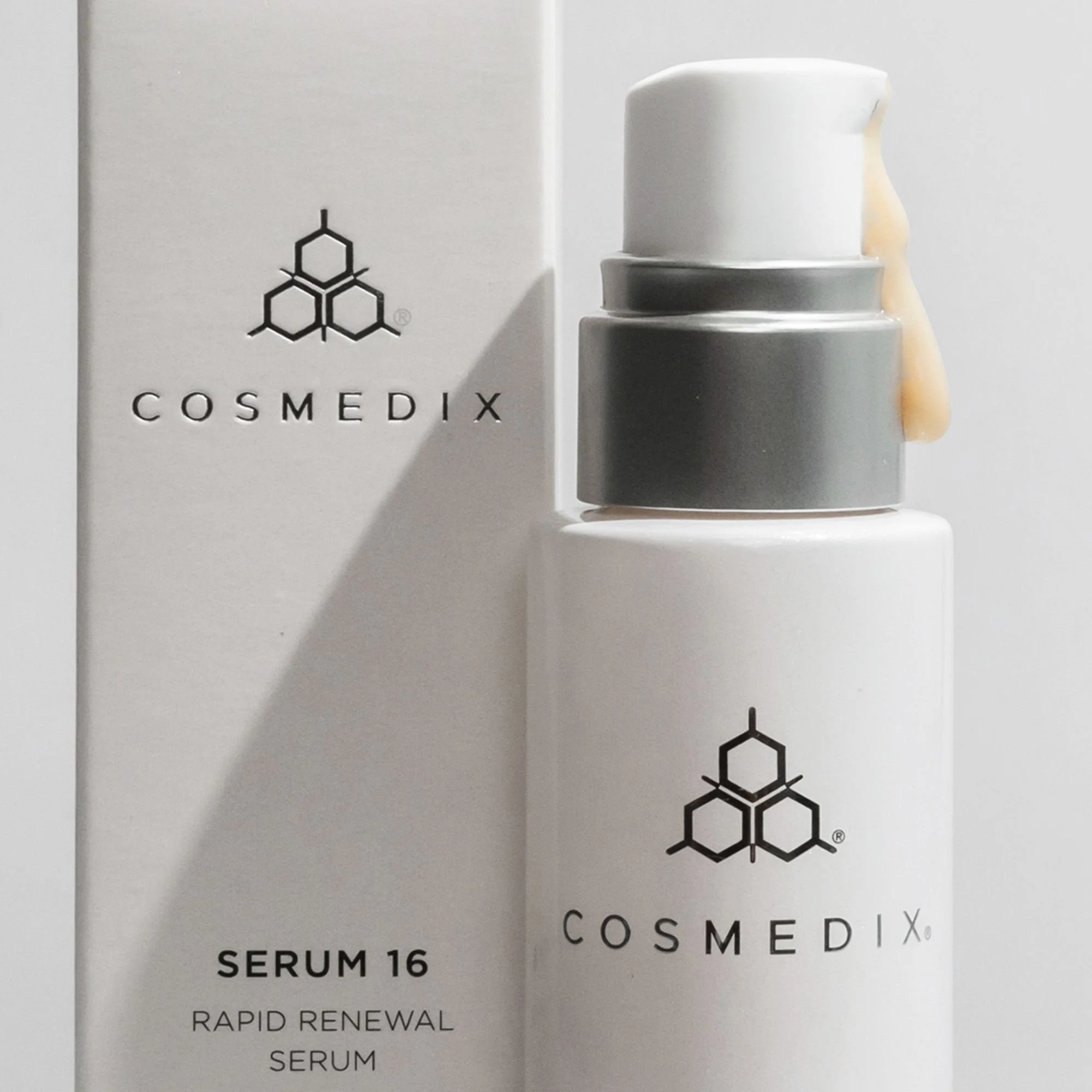 Close-up of COSMEDIX Serum 16 with a cream-colored serum swatch on the pump and its carton behind.
