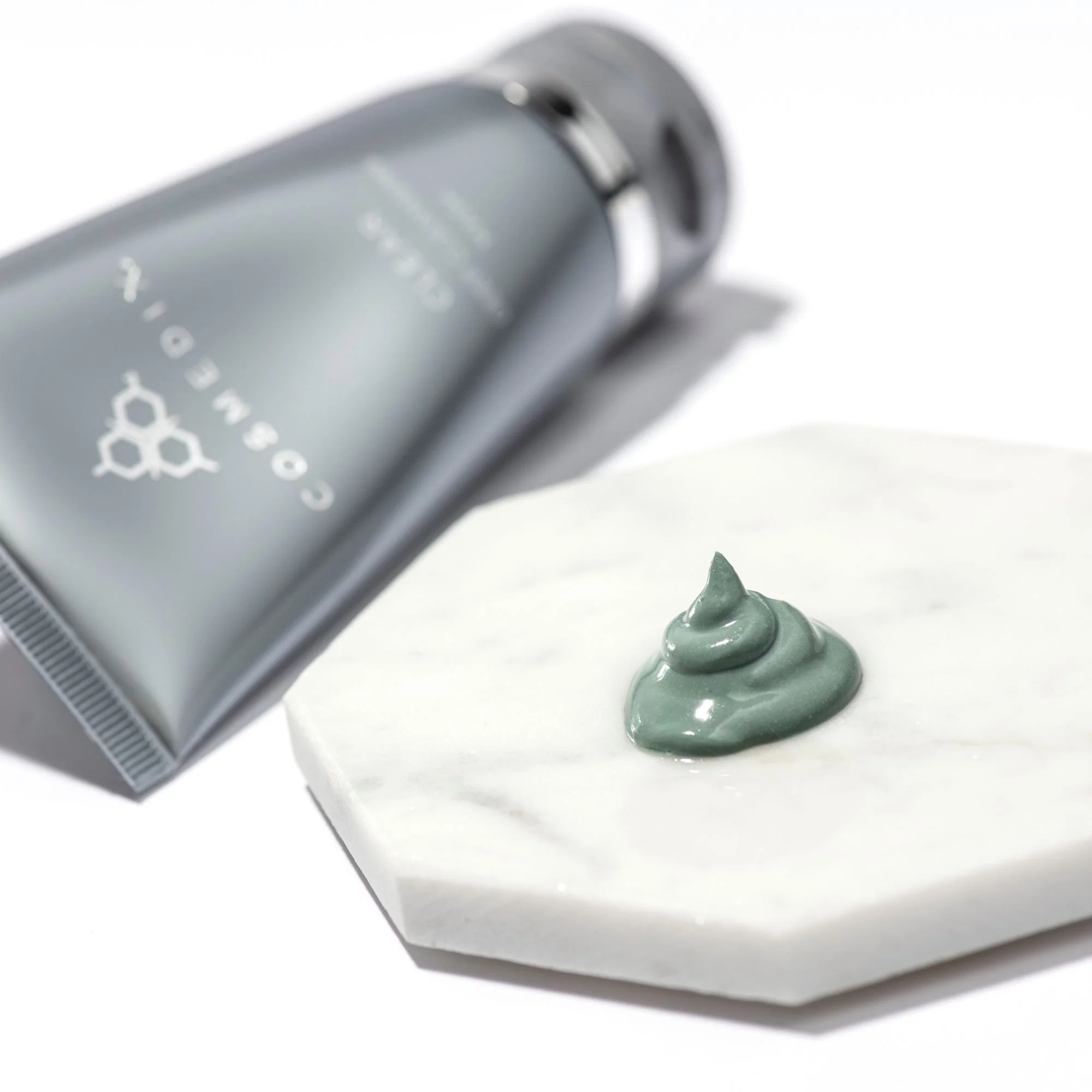 Blue-green COSMEDIX Clear mask on a white marble tray, with the product tube behind it.