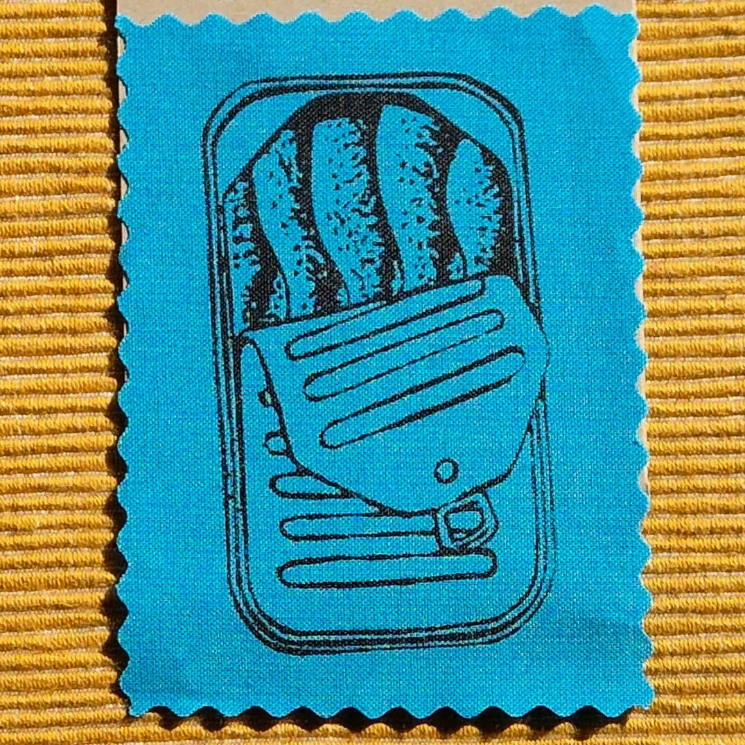 Blue fabric patch with an image of a sardine can printed on it
