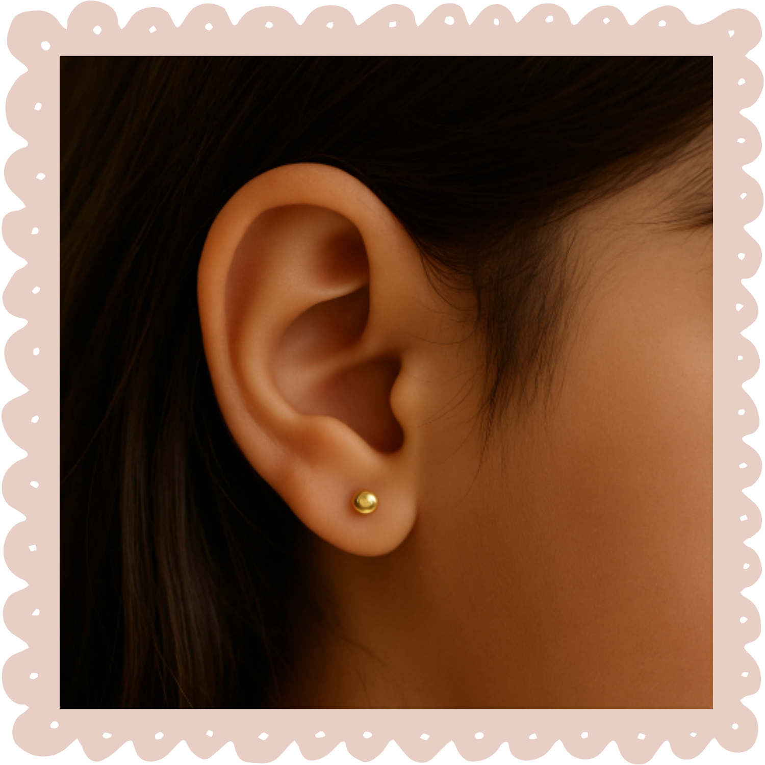 Close-up of a person's ear with a small gold stud earring, dark hair, and smooth skin visible.