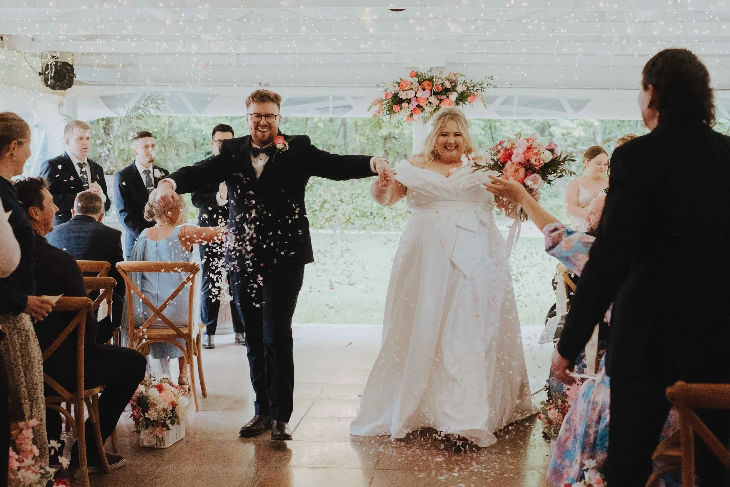newlyweds exiting the ceremony with confetti all around them newlyweds exiting the ceremony with confetti all around them
