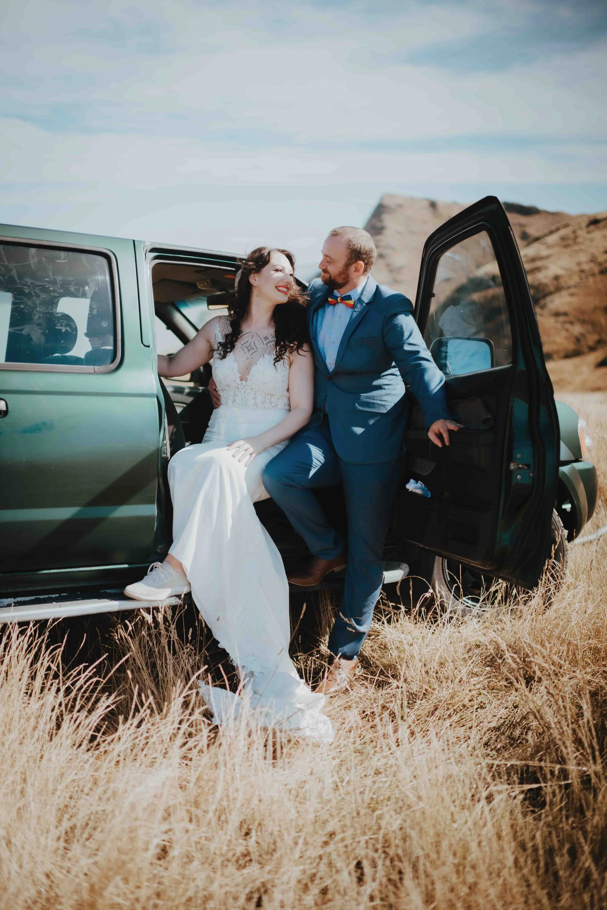 newlyweds sitting in the door of their ute smiling newlyweds sitting in the door of their ute smiling