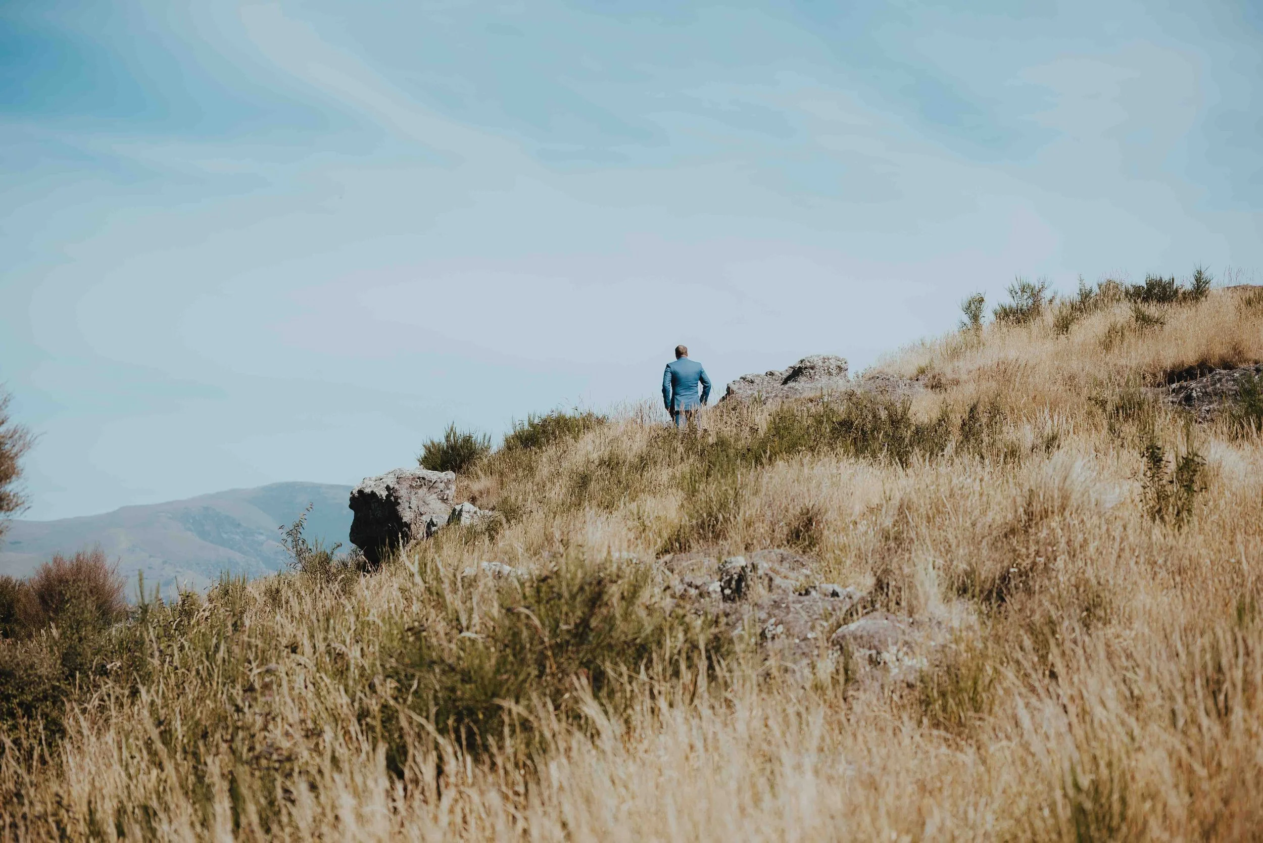 groom standing on the hills for their first look groom standing on the hills for their first look