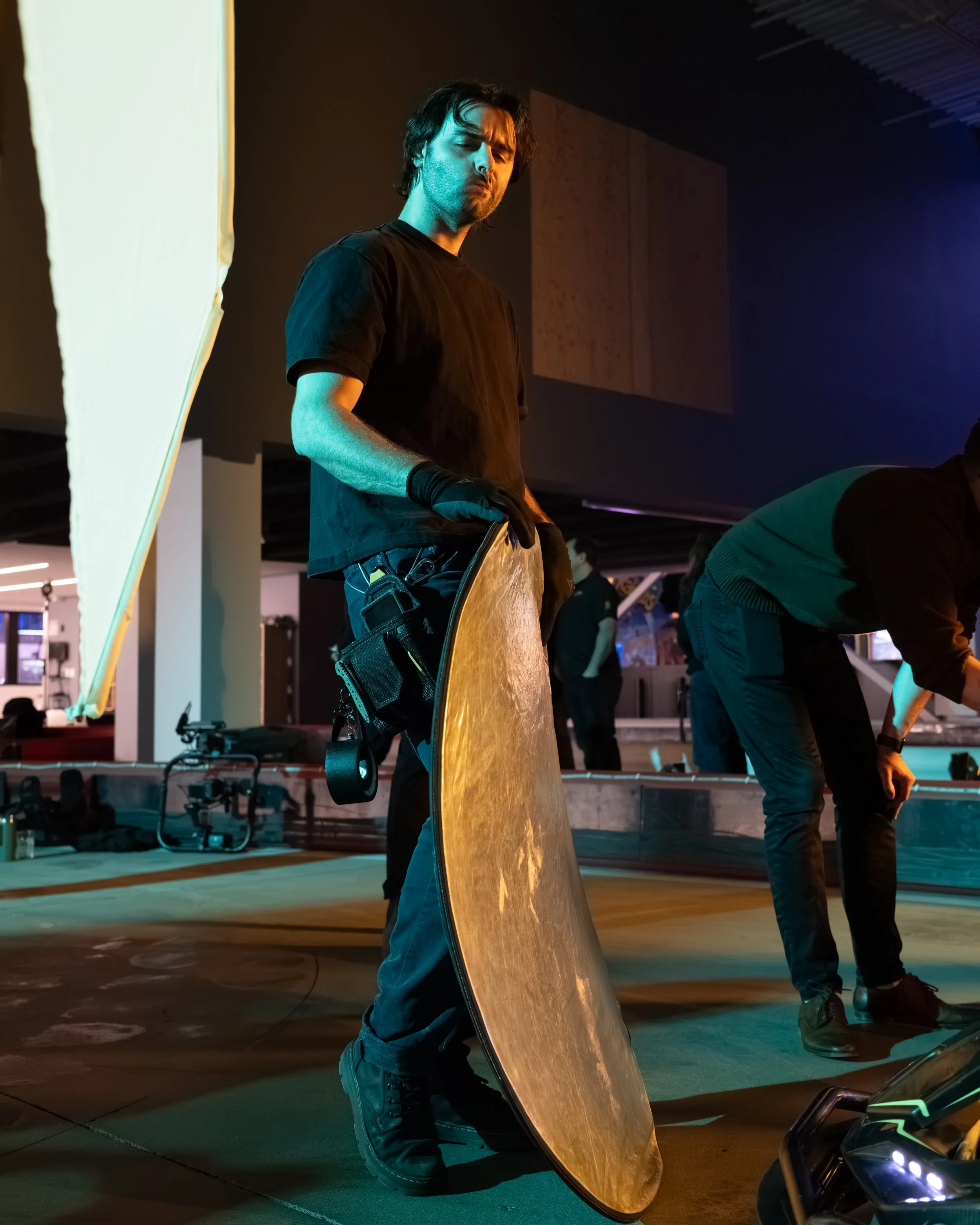 Gaffer Kyle Ruggiero holds a reflector on set