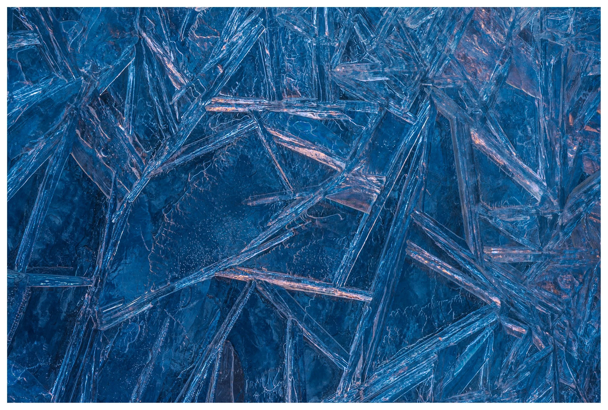 Close-up of blue ice crystals with sharp, angular patterns and reflections.