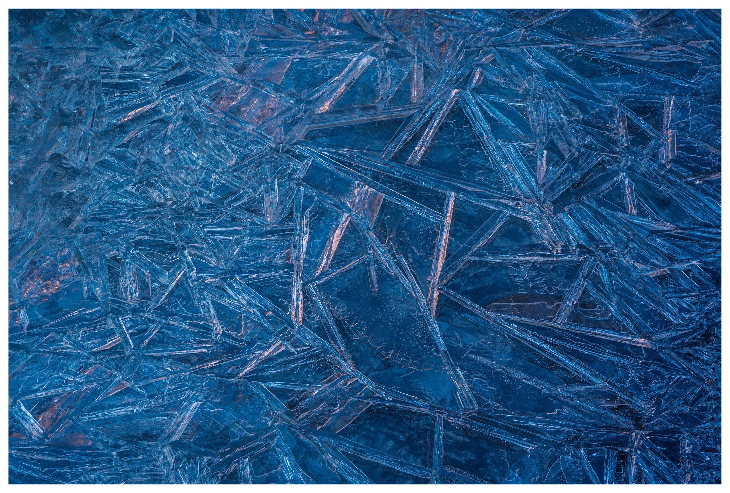 Close-up of blue ice crystals with sharp, angular patterns and reflections.