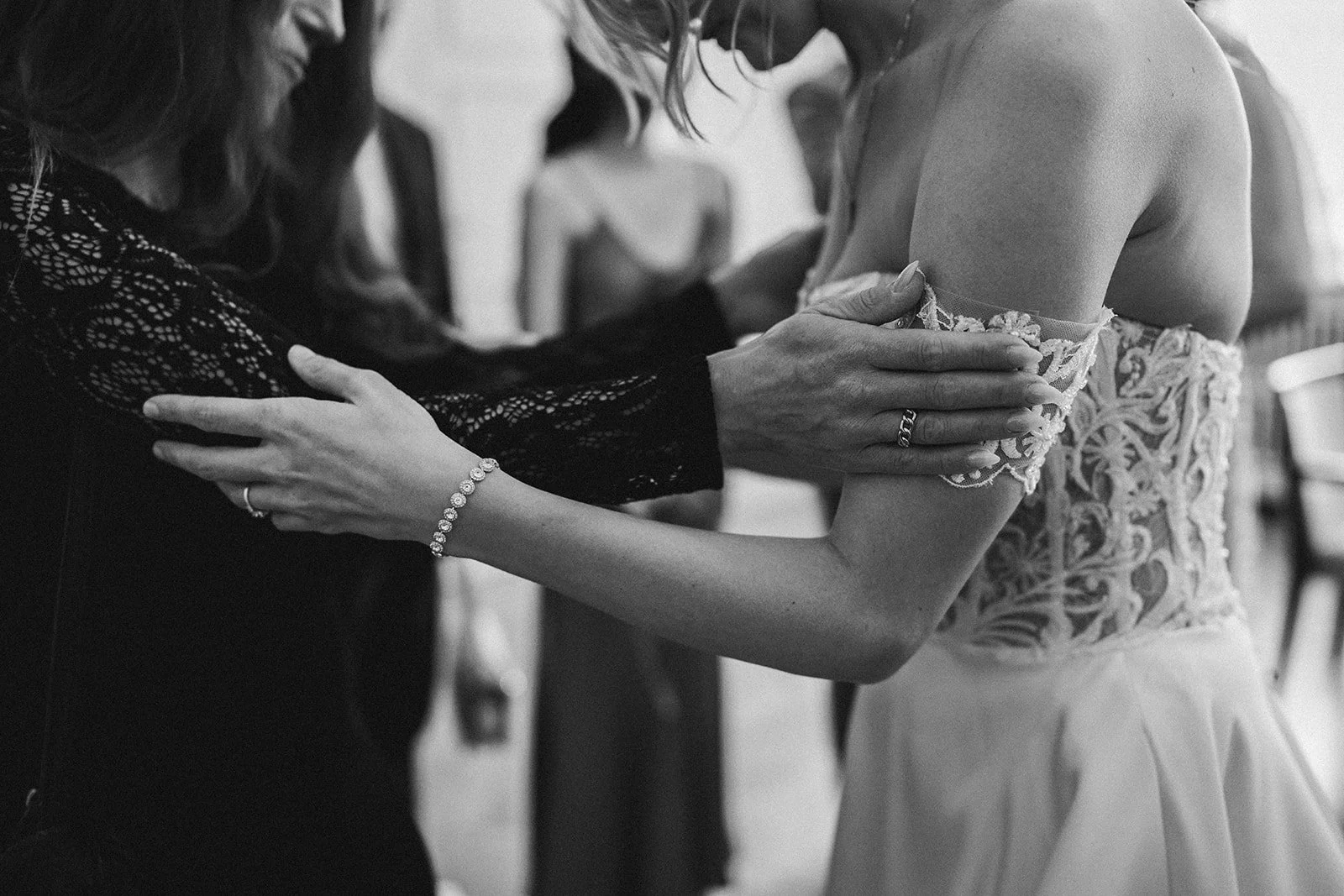 Eine Person hilft einer Braut beim Anziehen eines Hochzeitskleides bei einer Hochzeit. Die Szene ist in Schwarz-Weiß gehalten.  Hochzeitsfotograf Standesamt Mainz