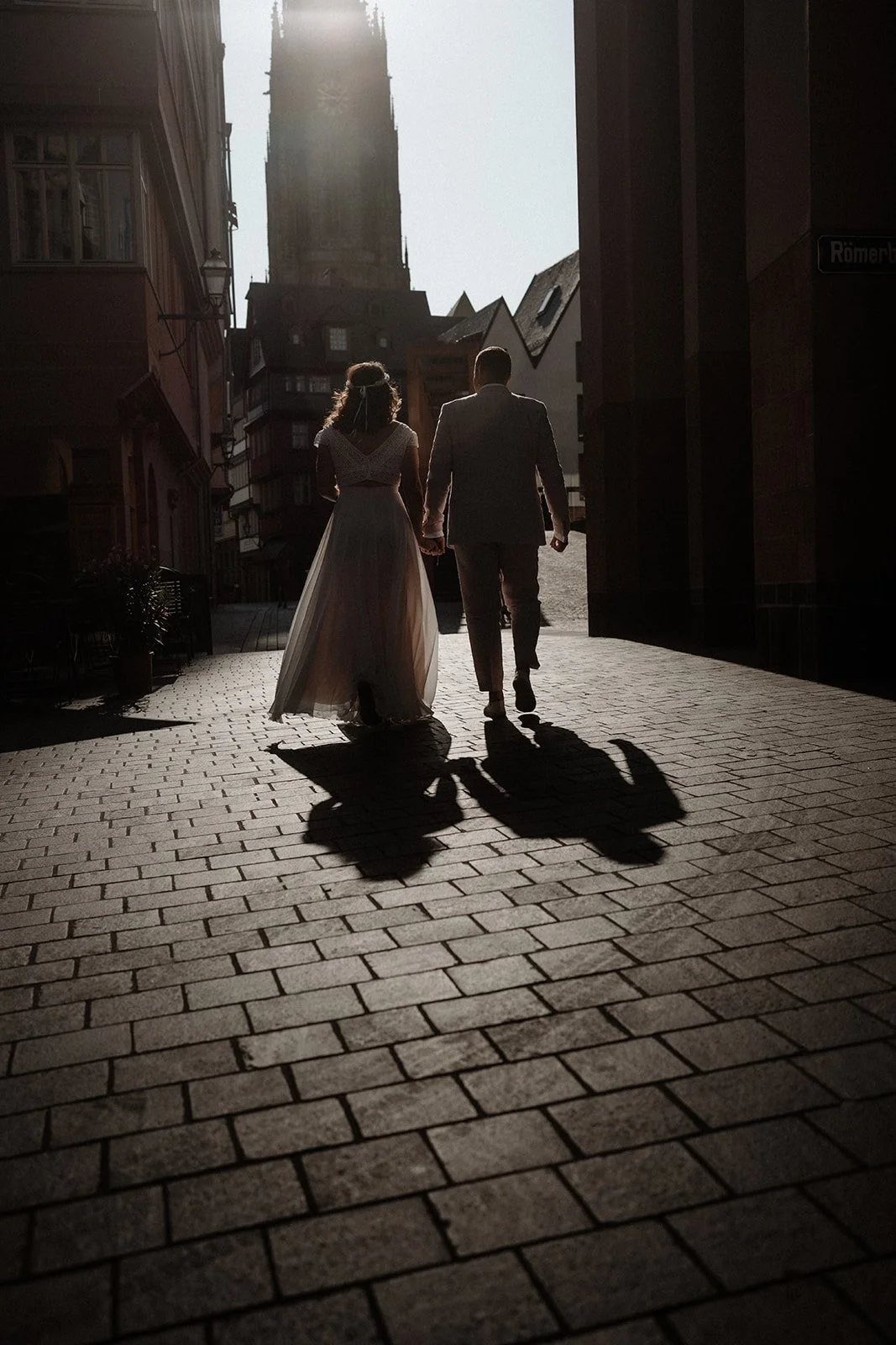 Brautpaar geht Hand in Hand auf einer Kopfsteinpflasterstraße in der Abenddämmerung – festgehalten vom Bart van Westrop, Hochzeitsfotograf in Mainz