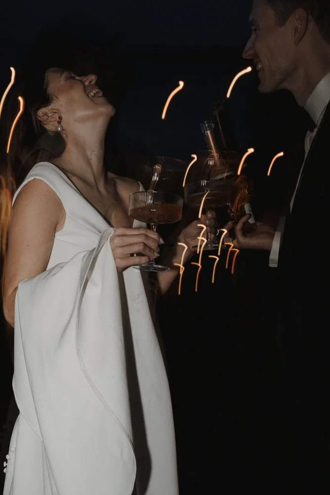 Paare bei einer eleganten Party, lachen und stoßen mit Getränken an, die im Dunkeln mit Funkenflug leuchten. Hochzeitsfotograf Wiesbaden Bart van Westrop