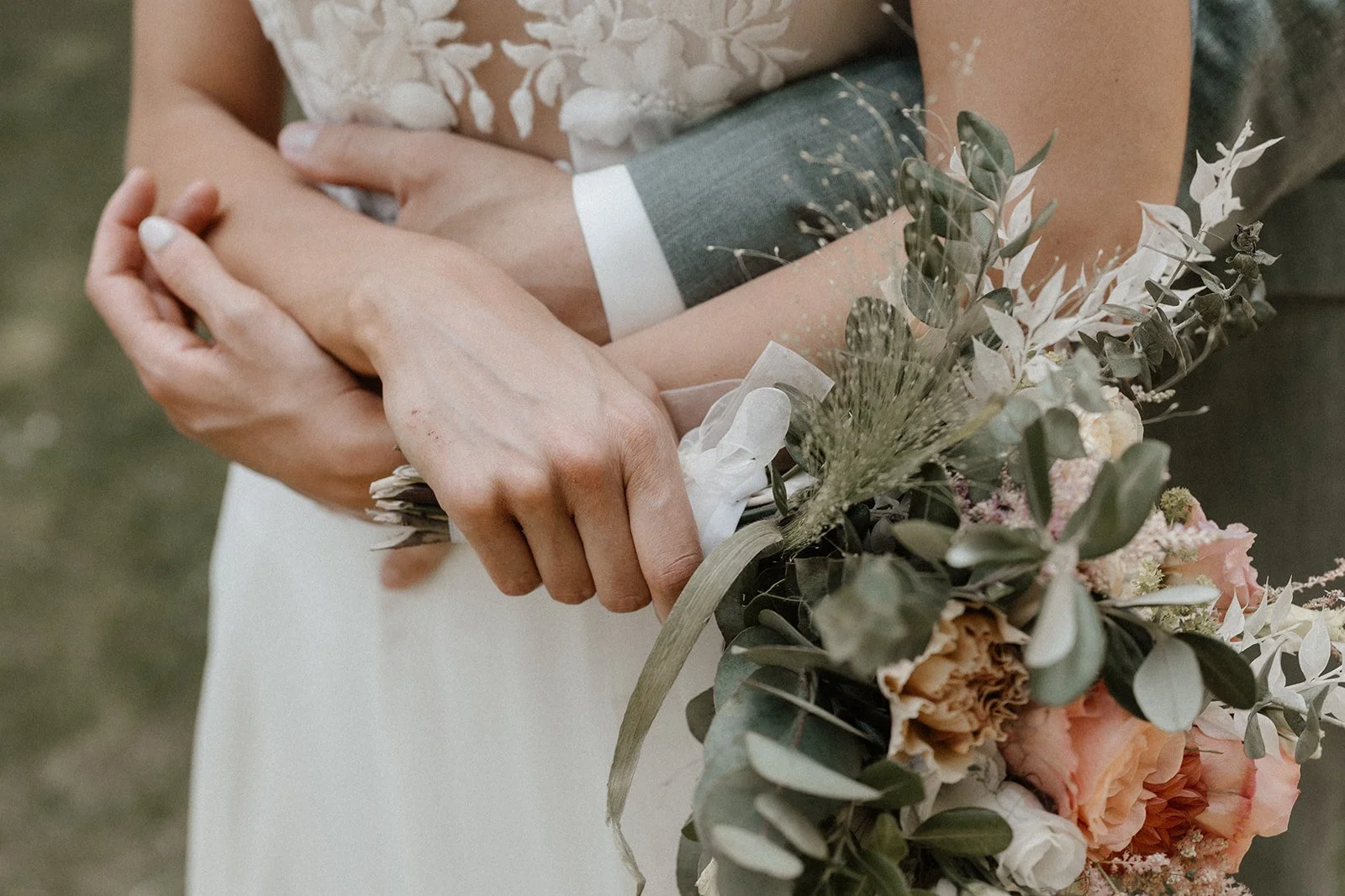 Brautpaar mit verschränkten Armen und Brautstrauß im Detail bei einer Hochzeit in Mainz, fotografiert von van Westrop Photography.