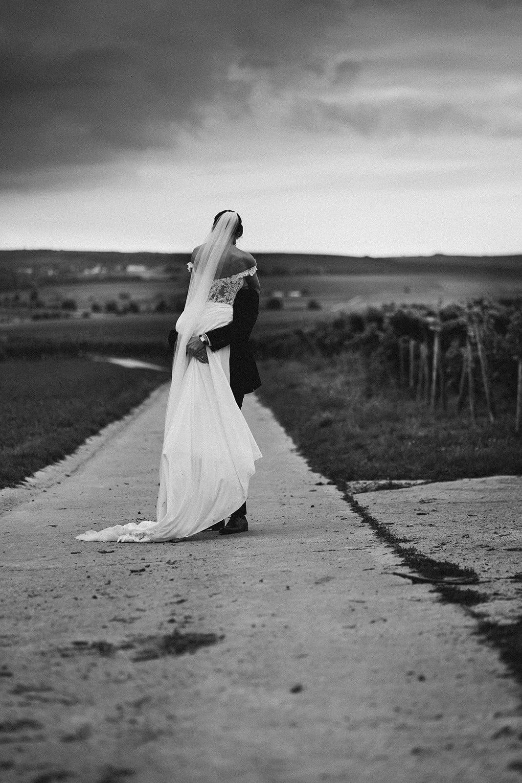 Ein Brautpaar auf einer Landstraße in einer ländlichen Gegend, schwarz-weiß-Foto, romantisches Hochzeitsfoto – festgehalten vom Bart van Westrop, Hochzeitsfotograf in Mainz