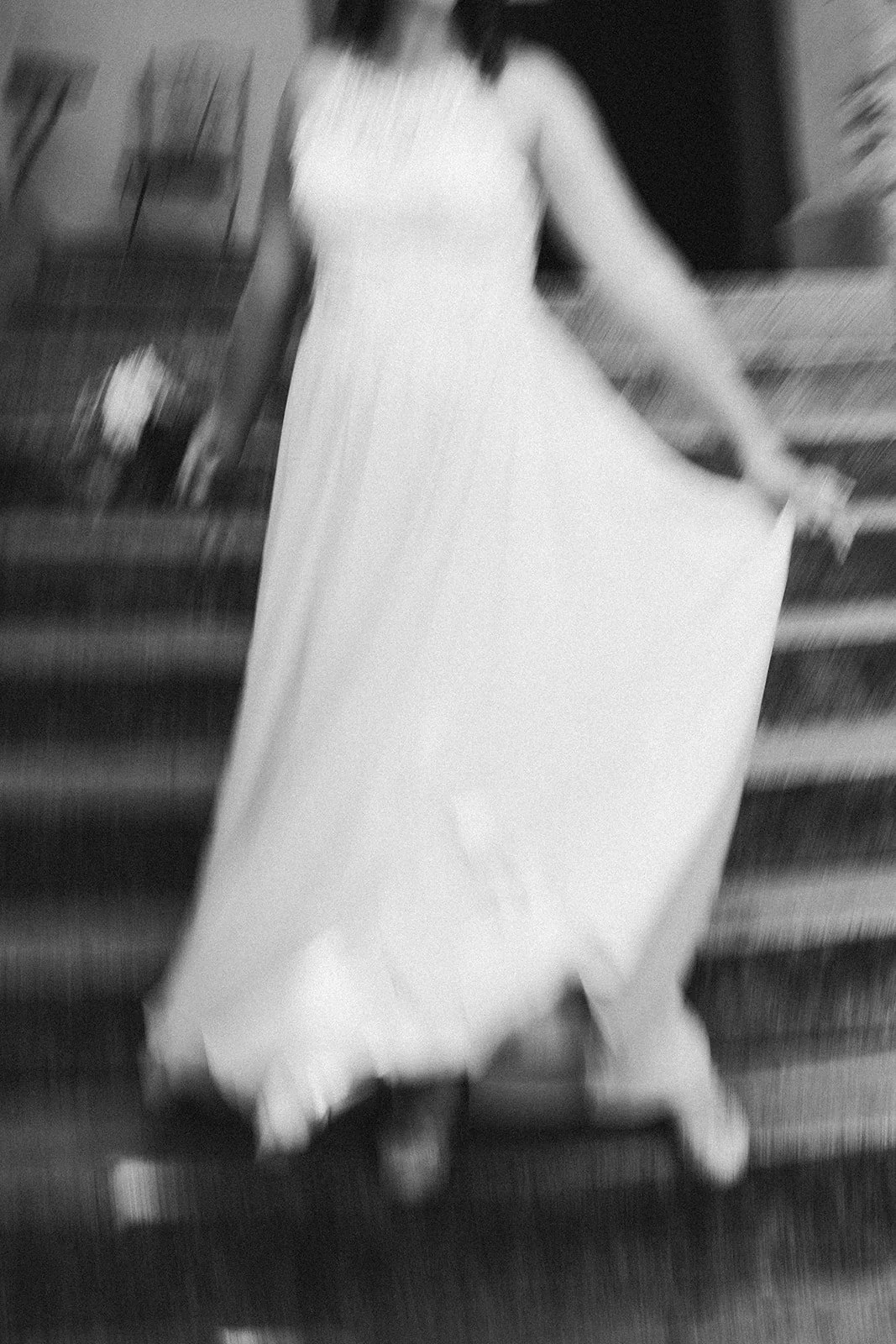 Eine Braut in einem langen weißen Kleid, die ein Kleid hält, steht auf einer Treppe.  Hochzeitsfotograf Standesamt Mainz