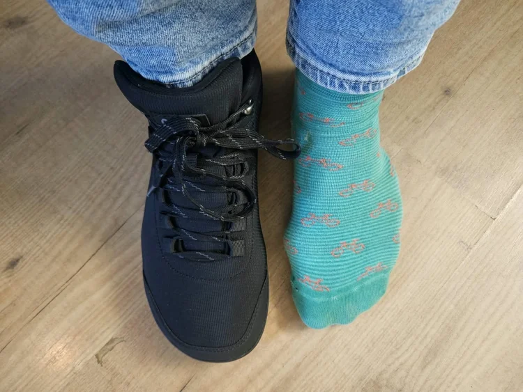 Freet Mist Black aan één voet, de andere voet in een sok, van bovenaf