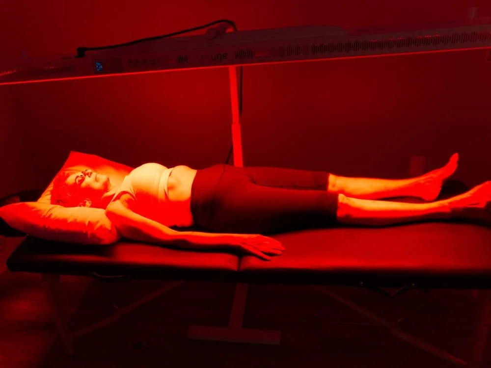 Woman lying on her back under red light therapy.