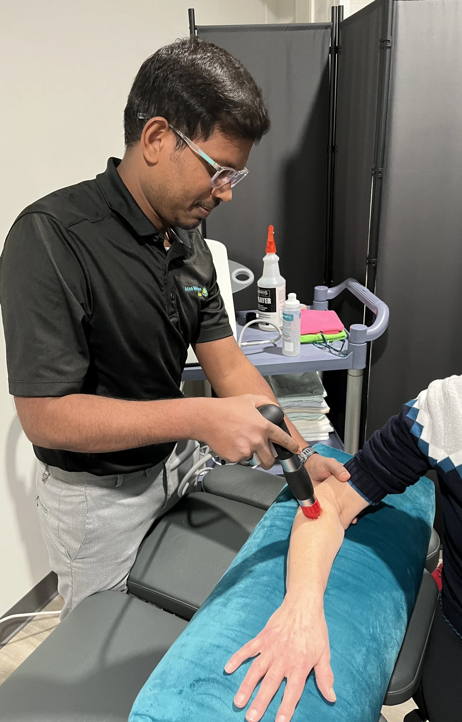 Deepsh performing a shockwave treatment on the arm of a client.