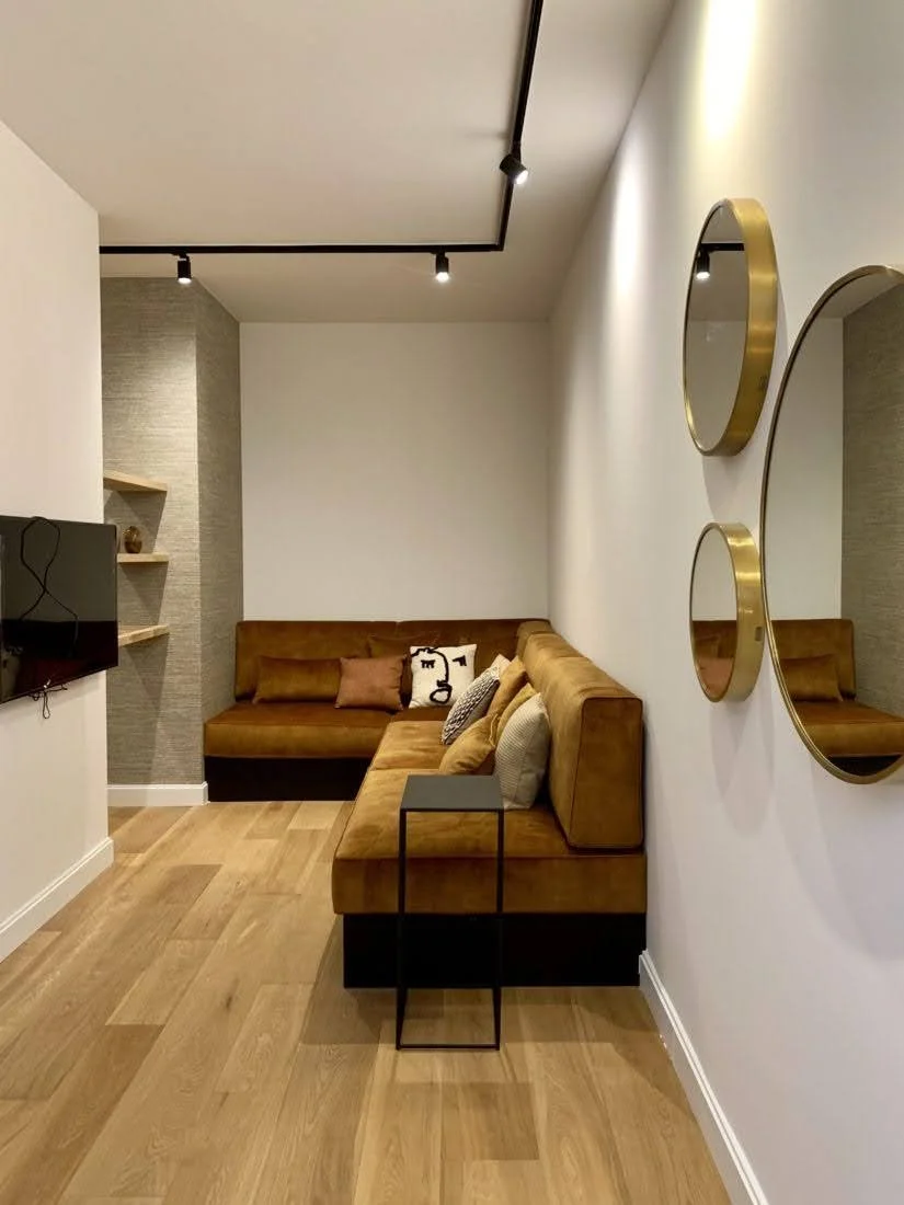 Gouden muurspiegels naast een bruine hoekbank in een modern ingerichte woonkamer