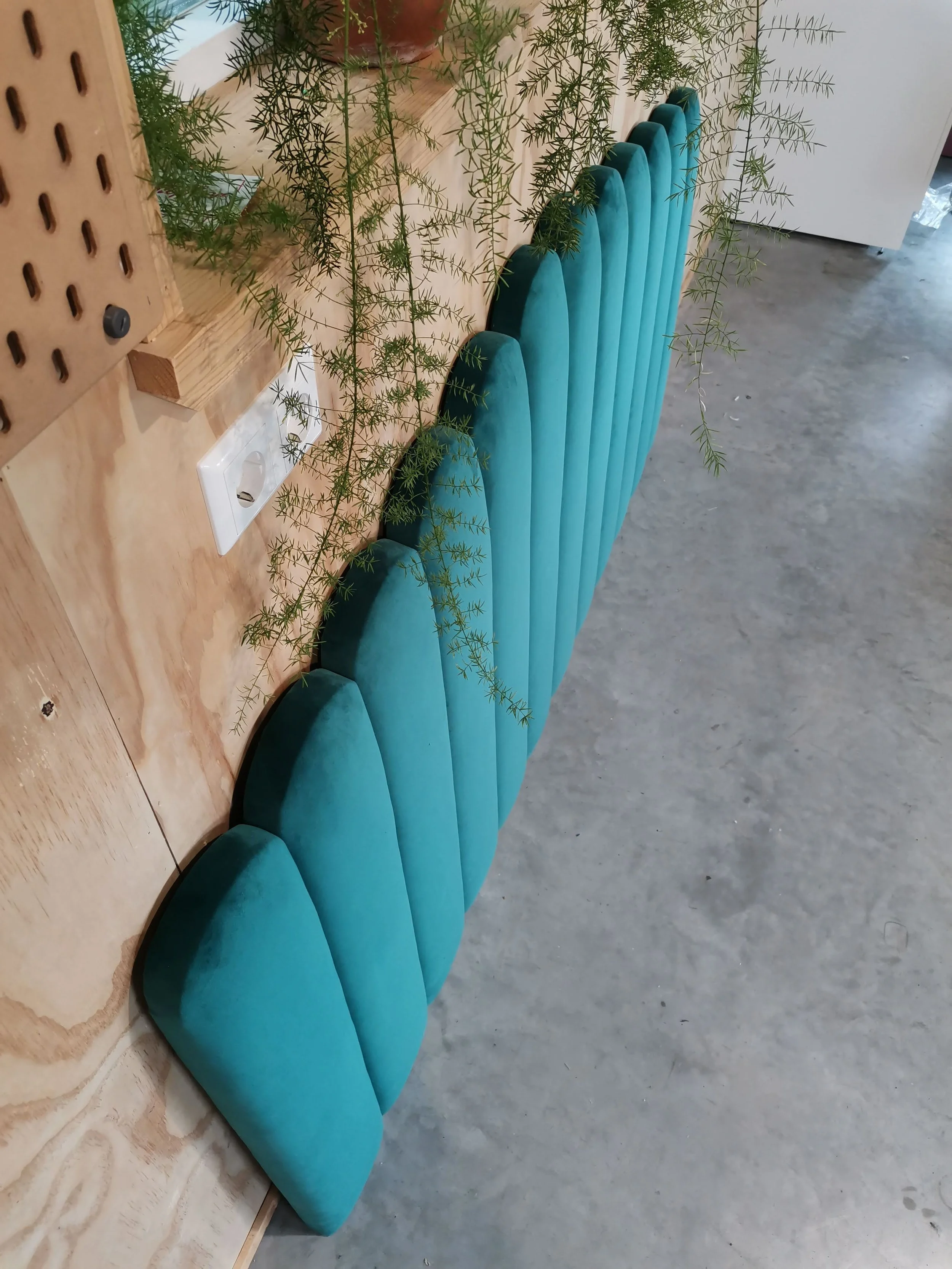 Bijzettafels in blauwe tinten, bovenaan een houtentafel met planten, op een vloer van beton.