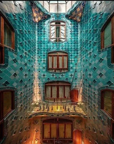 Interior view of a building with colorful mosaic walls and several windows, viewed from the ground looking up.