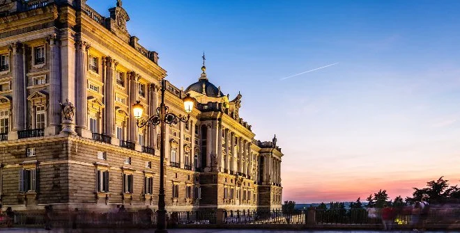 Historic European-style building during sunset with ornate architecture, street lamps, and a clear sky.