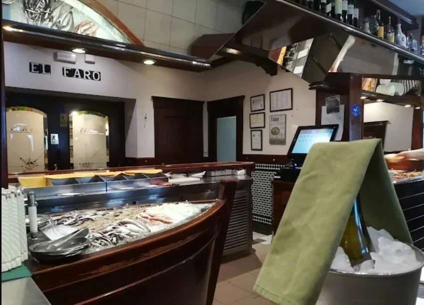 Fish display case in a seafood restaurant with a cash register, a wash basin, and framed certificates on the wall.
