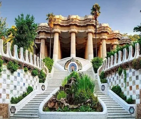 A colorful and ornate building with columns, stairs, and lush greenery in a garden setting.