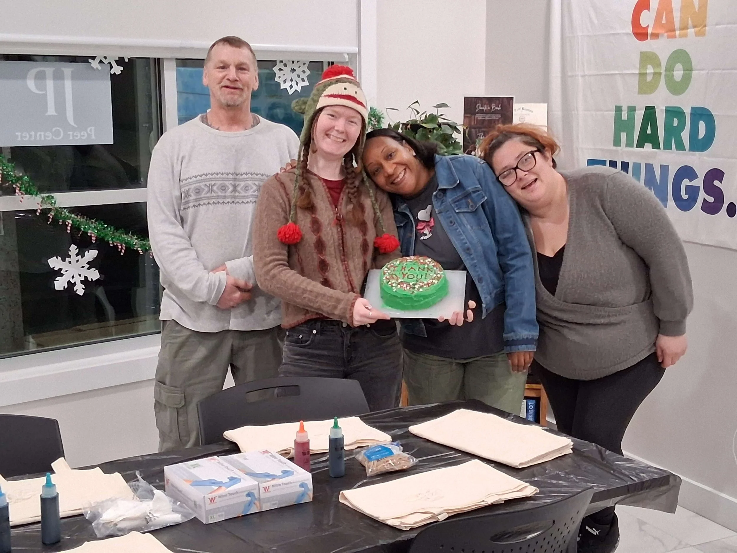 Group of four people celebrating around a birthday cake with Christmas decorations in the background.