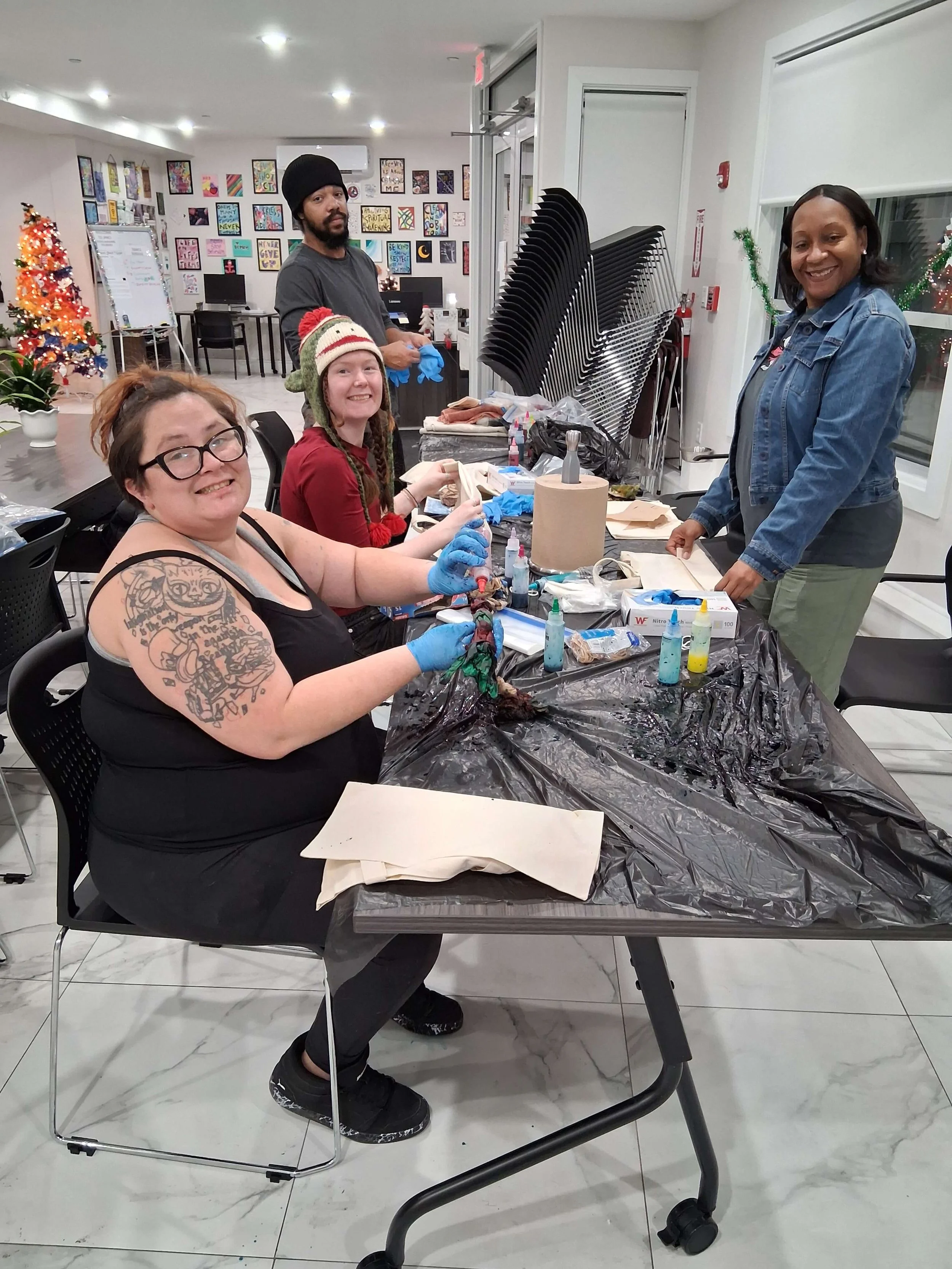 People participating in a holiday-themed art activity at a table inside a decorated room with Christmas decorations.