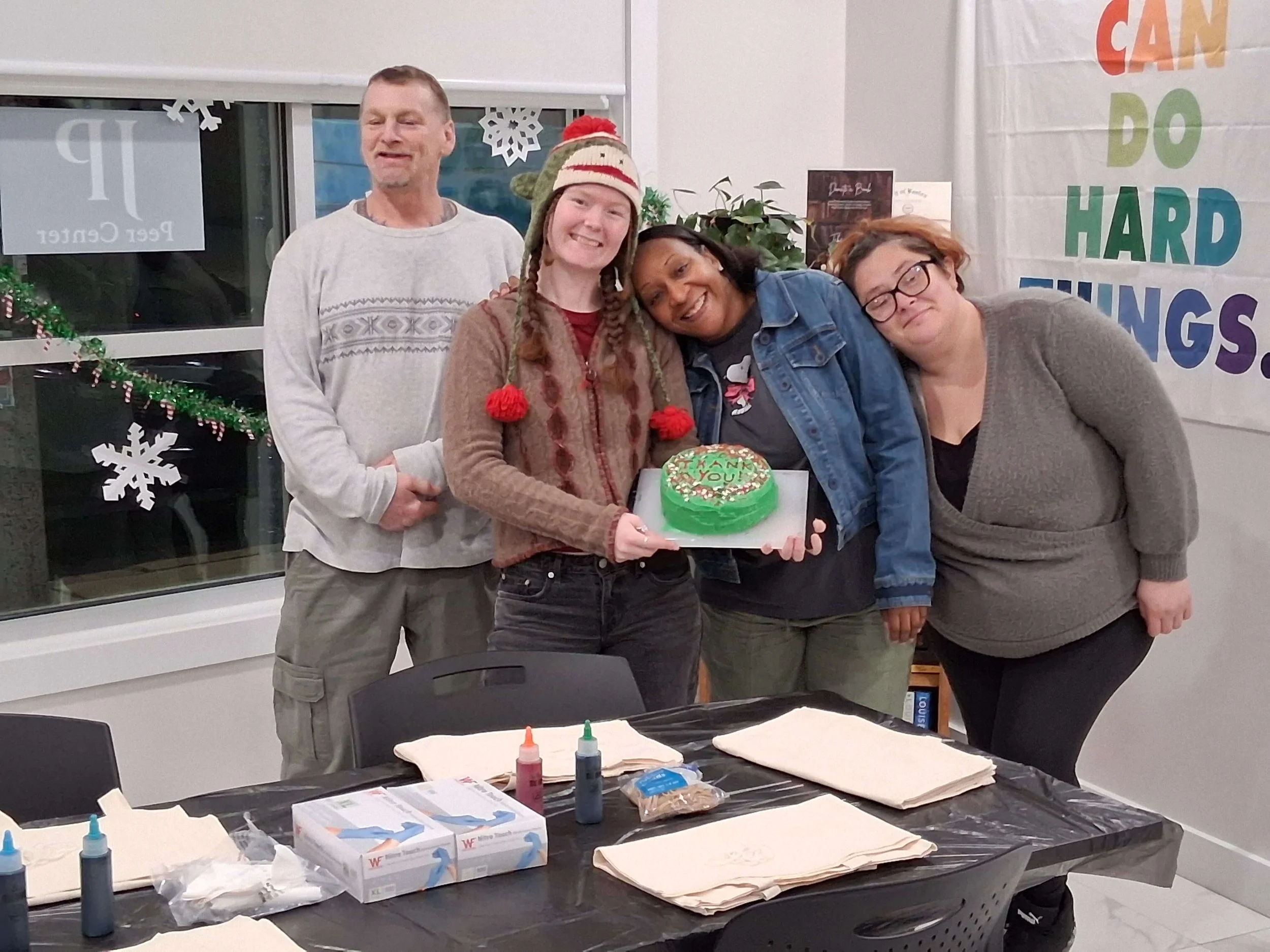 Group of five people celebrating with a Christmas cake in a room decorated for the holidays.