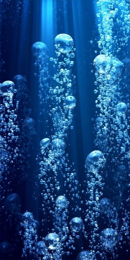 Underwater scene with bubbles rising towards the surface, illuminated by rays of light.