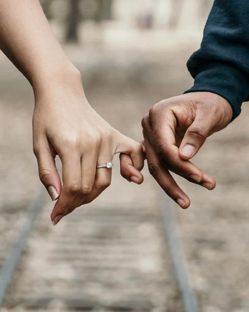 young engaged couple holding hands outside