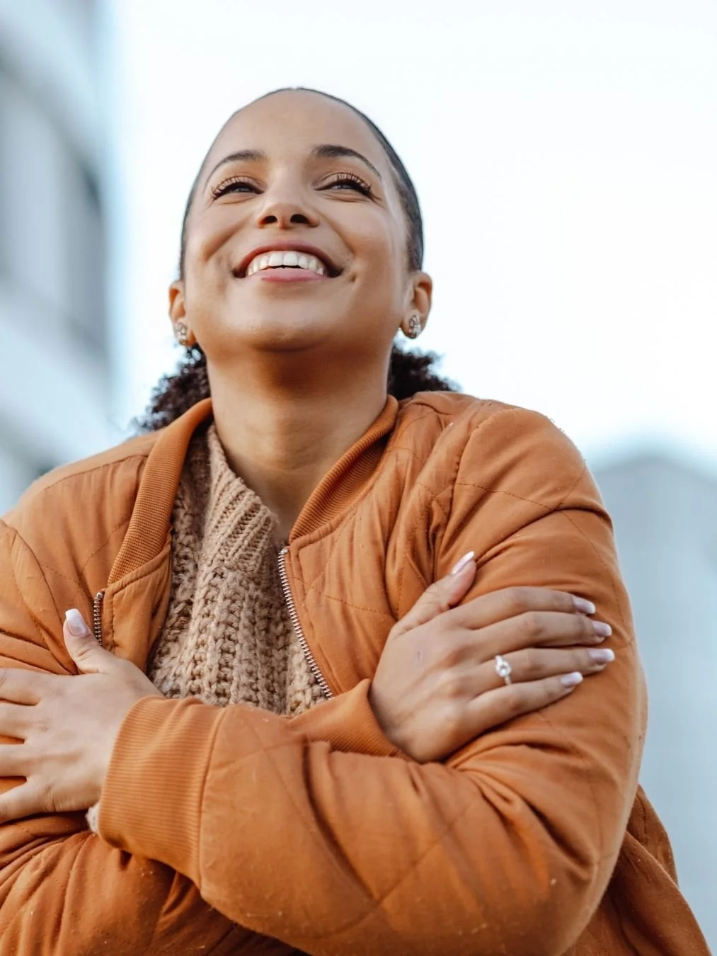 Woman wearing a brown jacket hugging herself