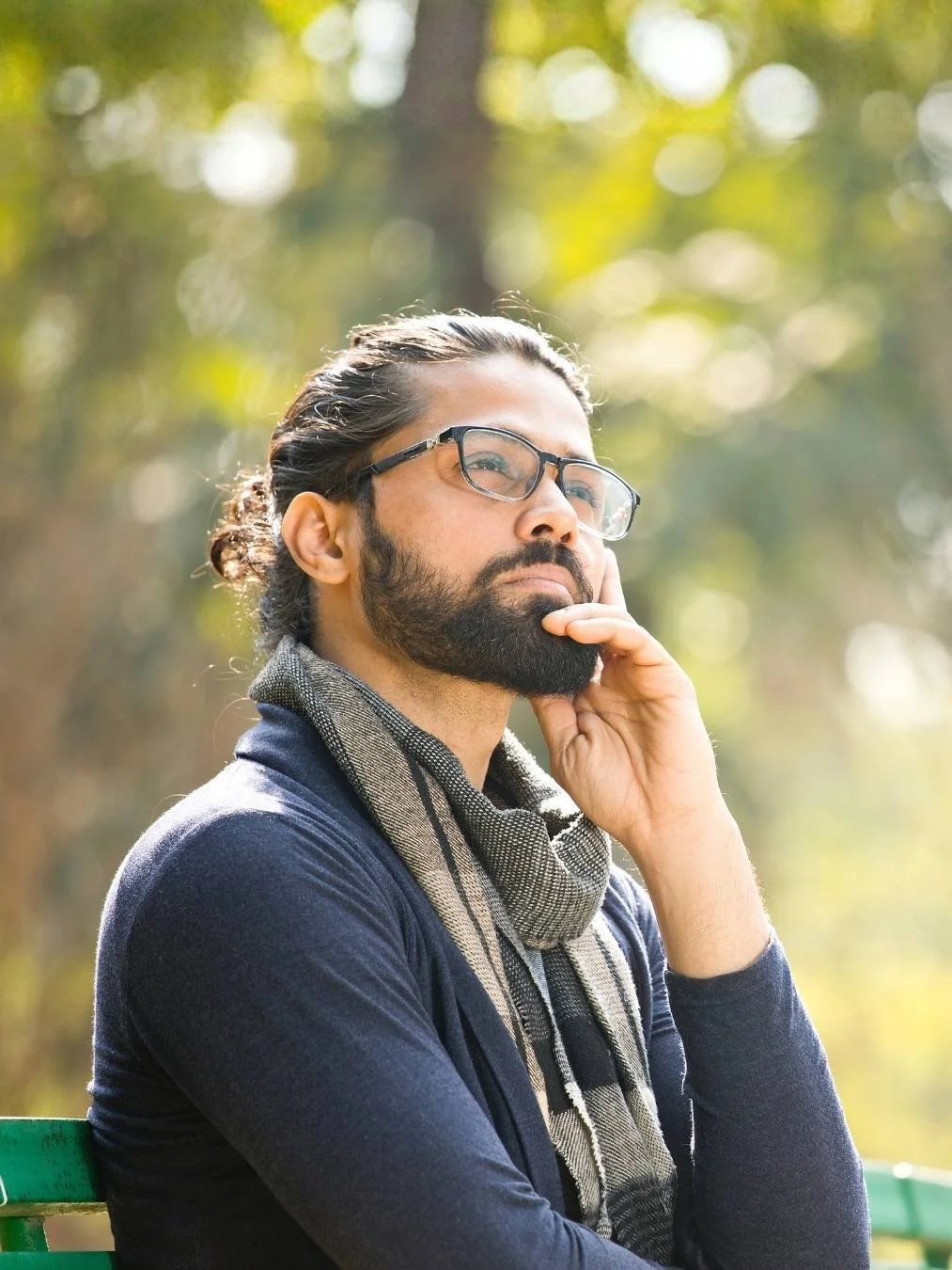 Young man sitting on a park bench thinking