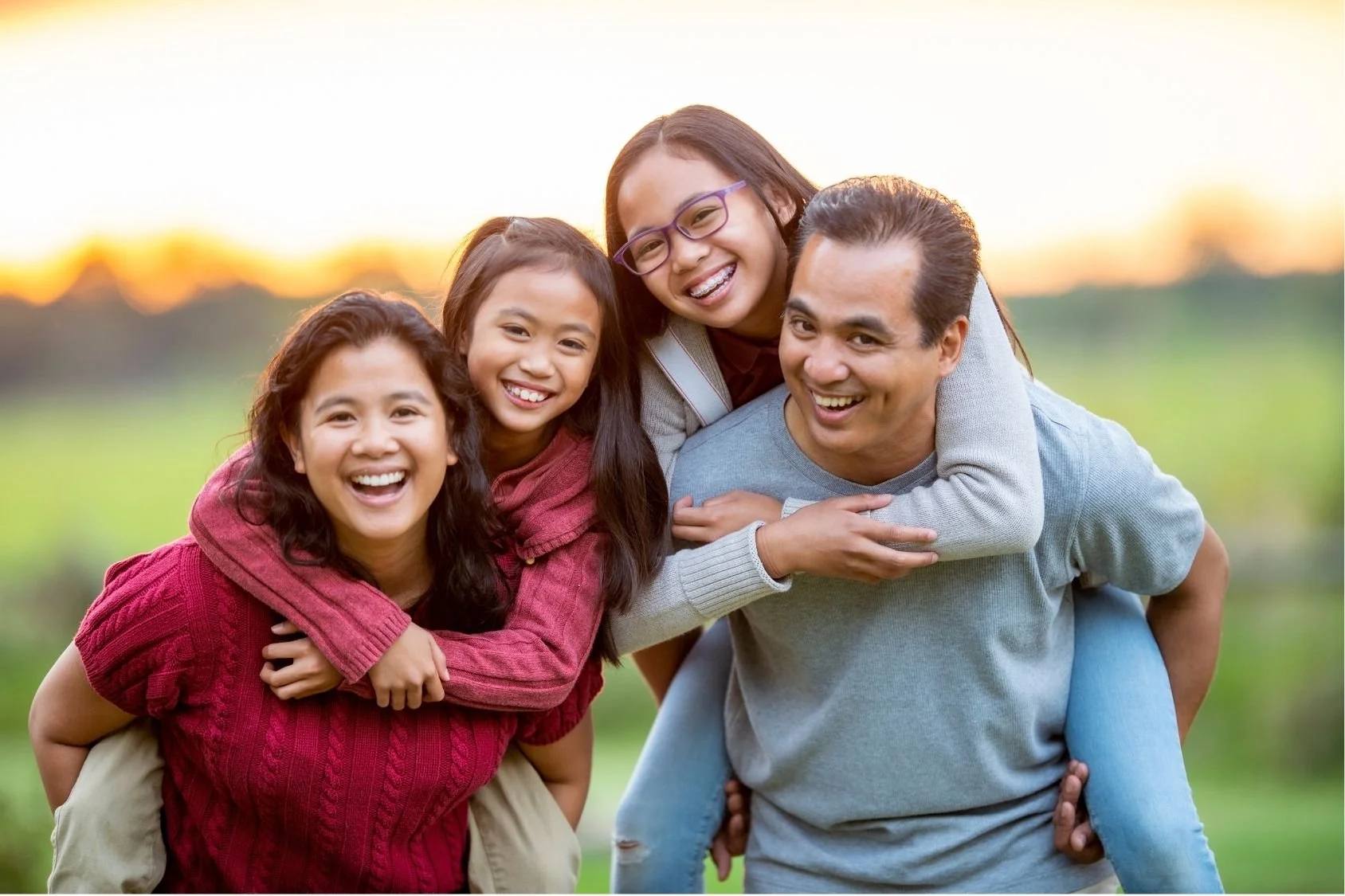 Family of four laughing together doing piggybacks 