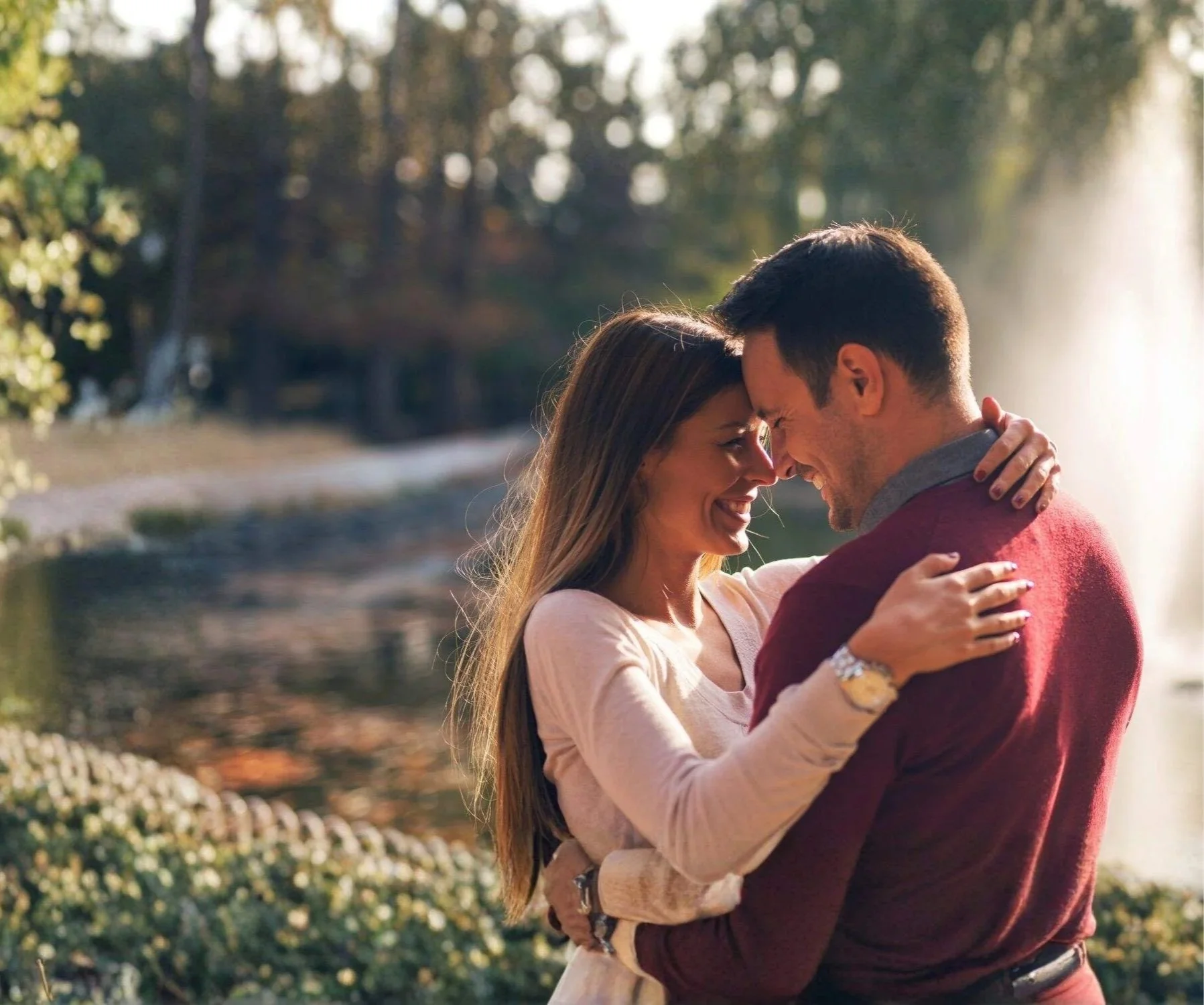 Couple looking at eachother and embracing by a water fountain