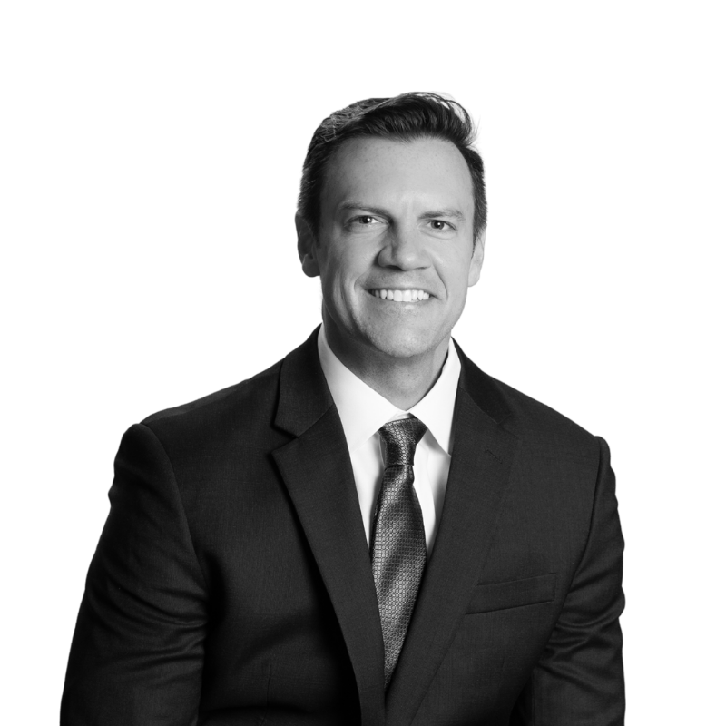 A professional black and white portrait of a man in a suit smiling.