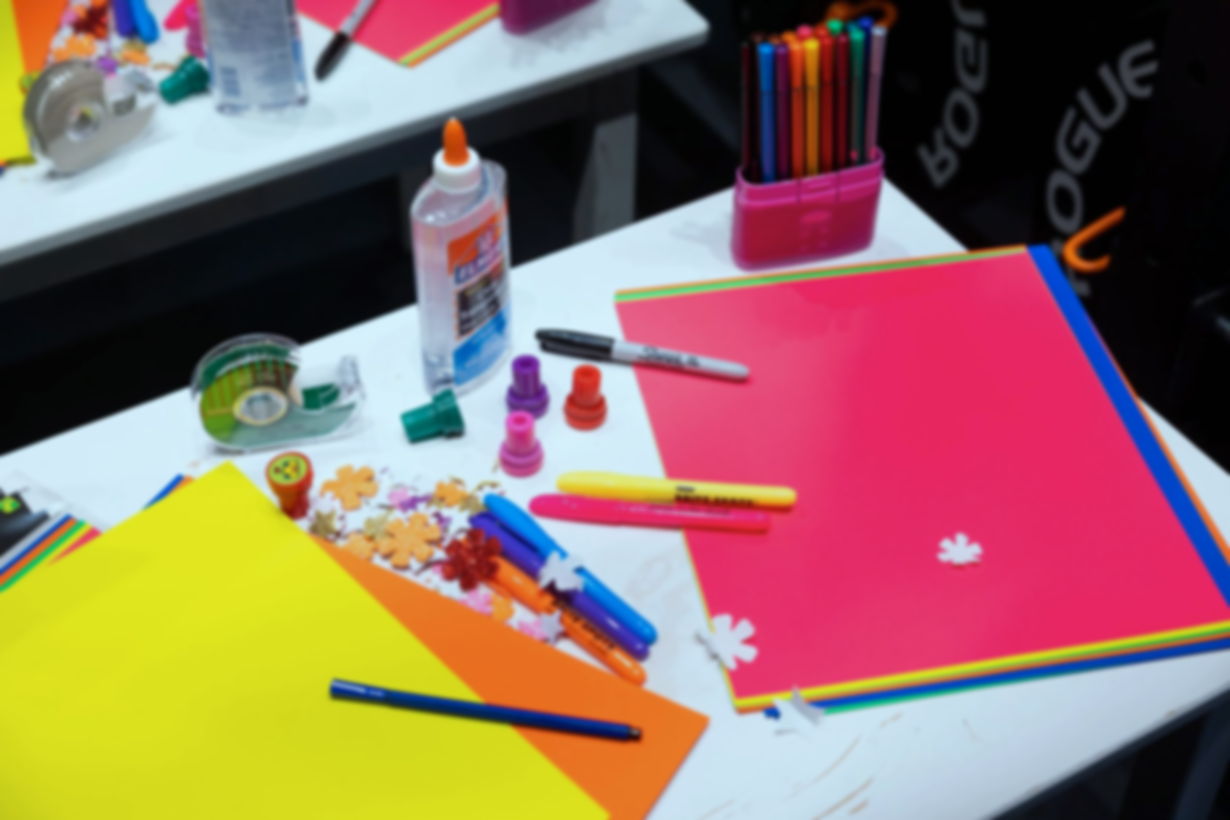 A table with various school and craft supplies, including colorful papers, markers, glue, and decorative items.