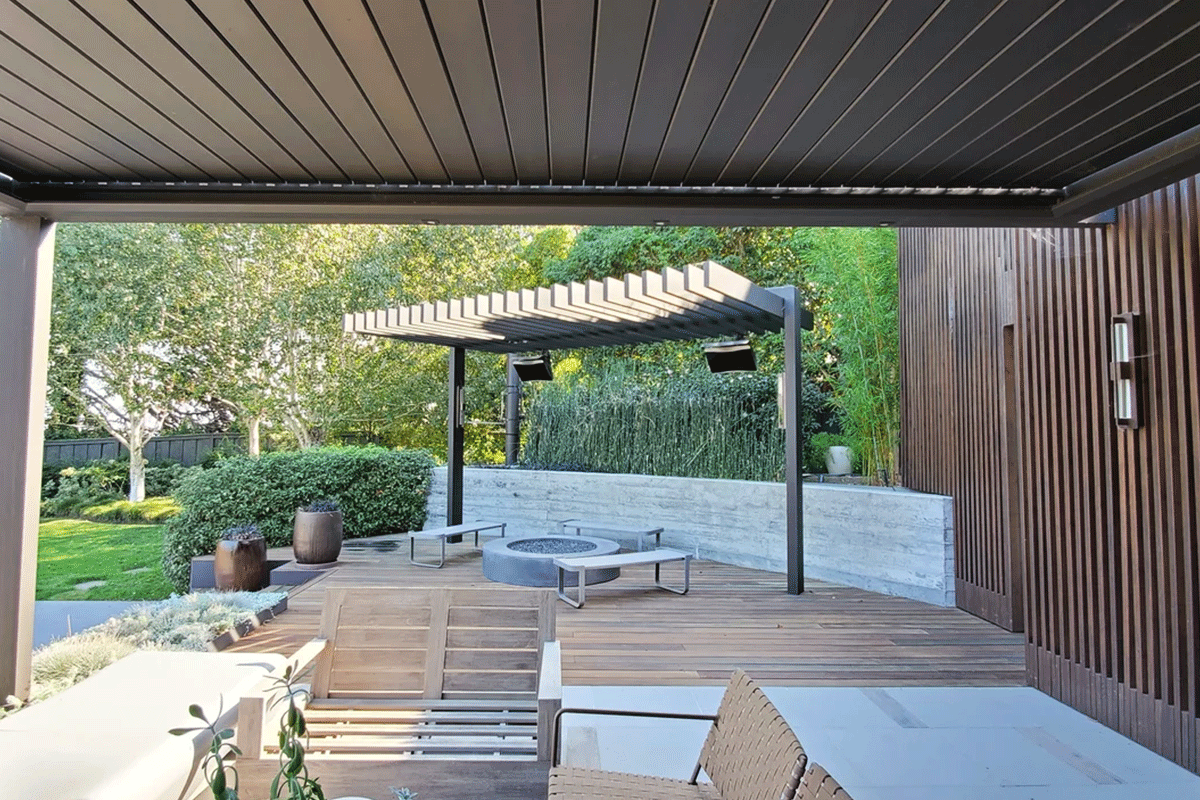Contemporary outdoor patio featuring a Louvretec 180 Linear louvered roof system with dark aluminium framing, providing adjustable shade over a wooden deck and seating area.