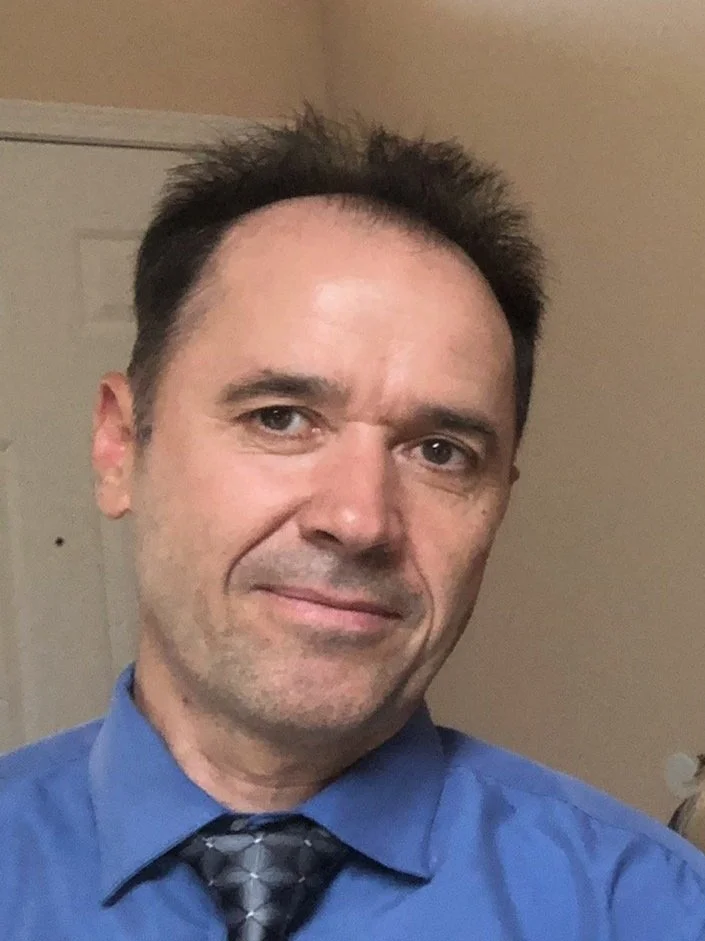 Person wearing a blue shirt and tie, smiling.
